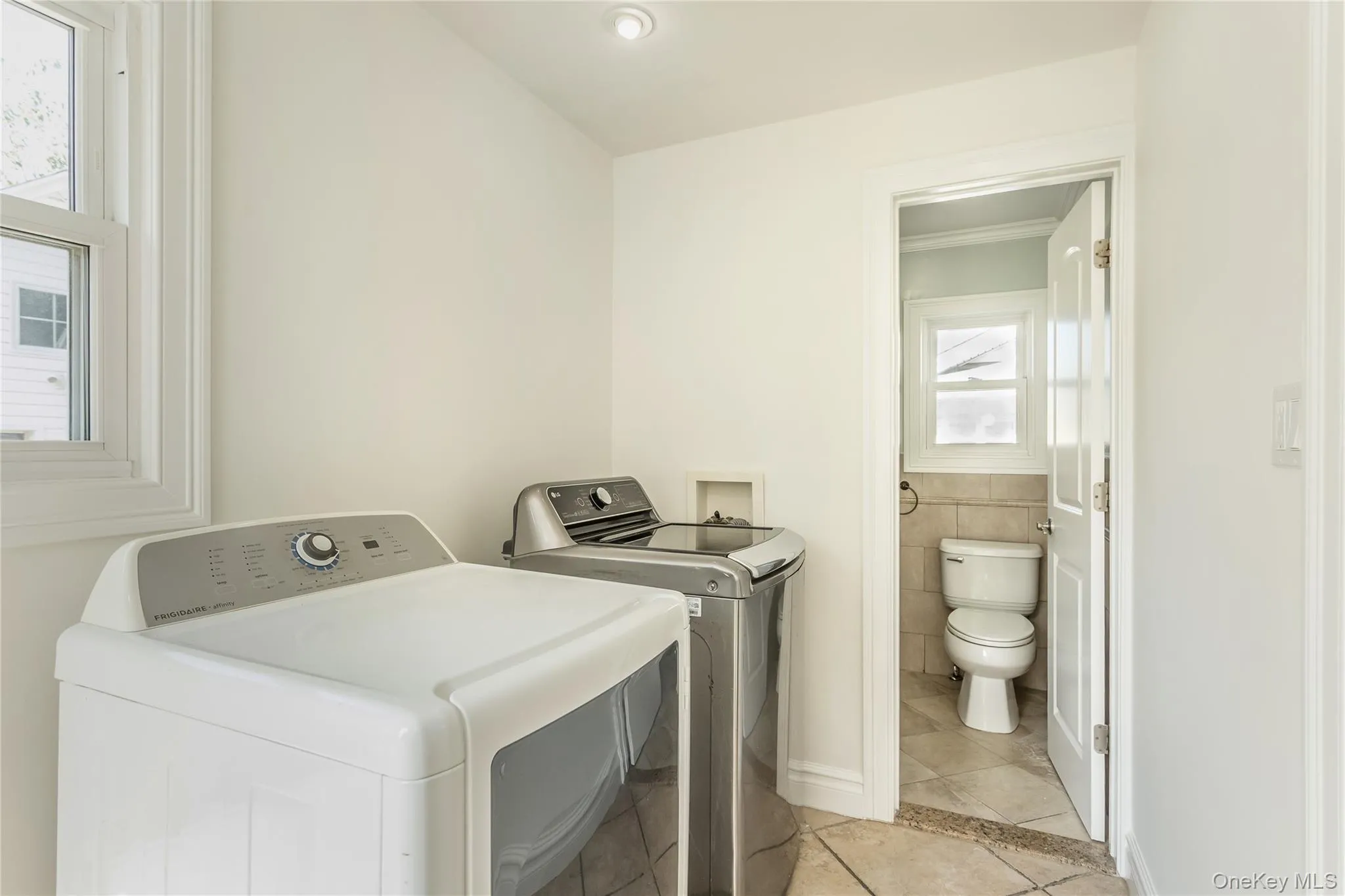 Laundry room with light tile patterned flooring and washing machine and dryer Laundry room with light tile patterned flooring and washing machine and dryer