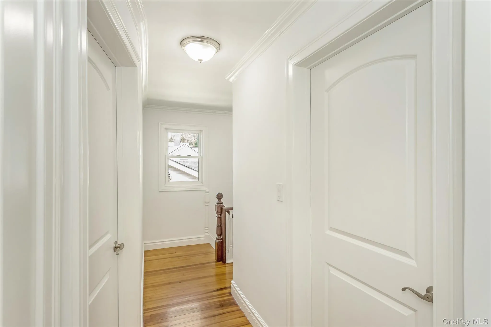 Hall with crown molding, light wood-style floors, and an upstairs landing Hall with crown molding, light wood-style floors, and an upstairs landing