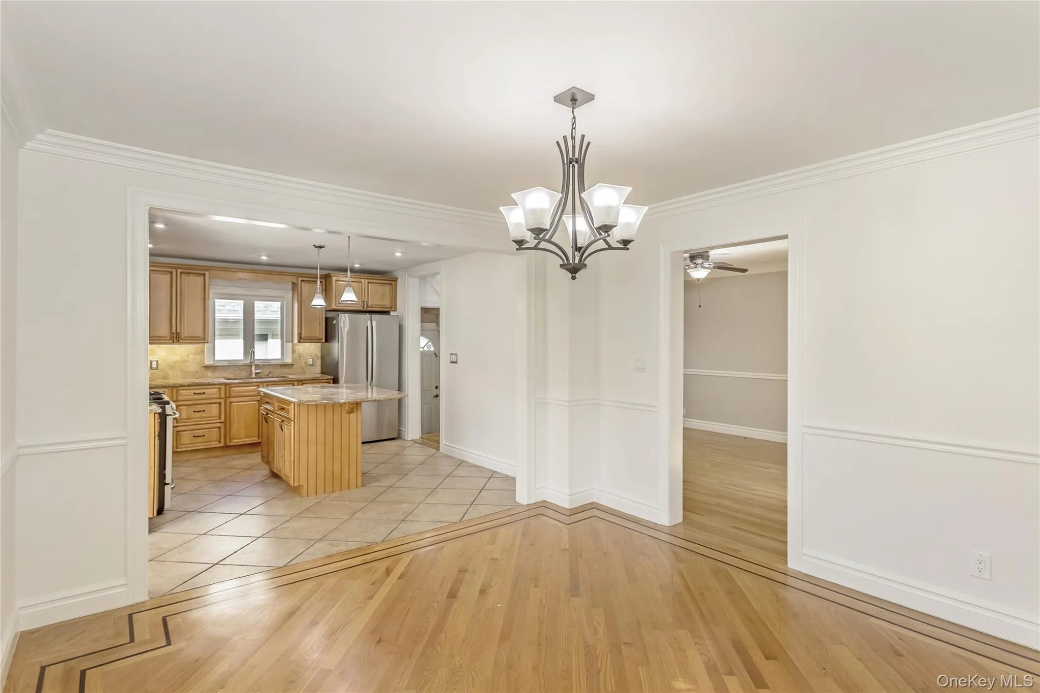 Unfurnished dining area with light wood-type flooring, crown molding, a ceiling fan, and a chandelier Unfurnished dining area with light wood-type flooring, crown molding, a ceiling fan, and a chandelier