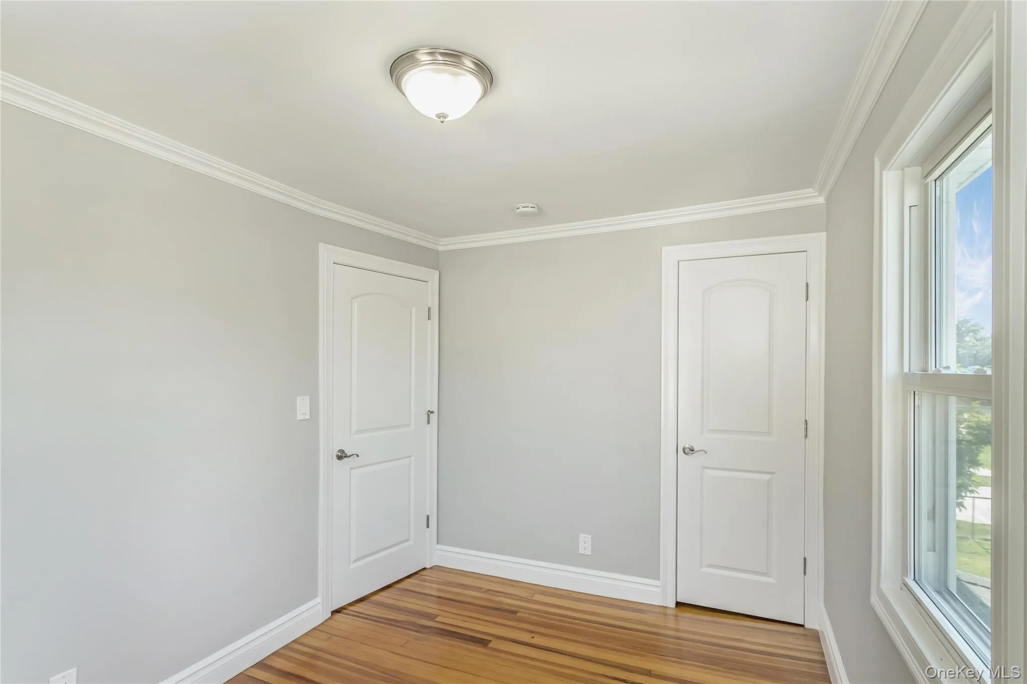 Unfurnished bedroom featuring crown molding and wood finished floors Unfurnished bedroom featuring crown molding and wood finished floors