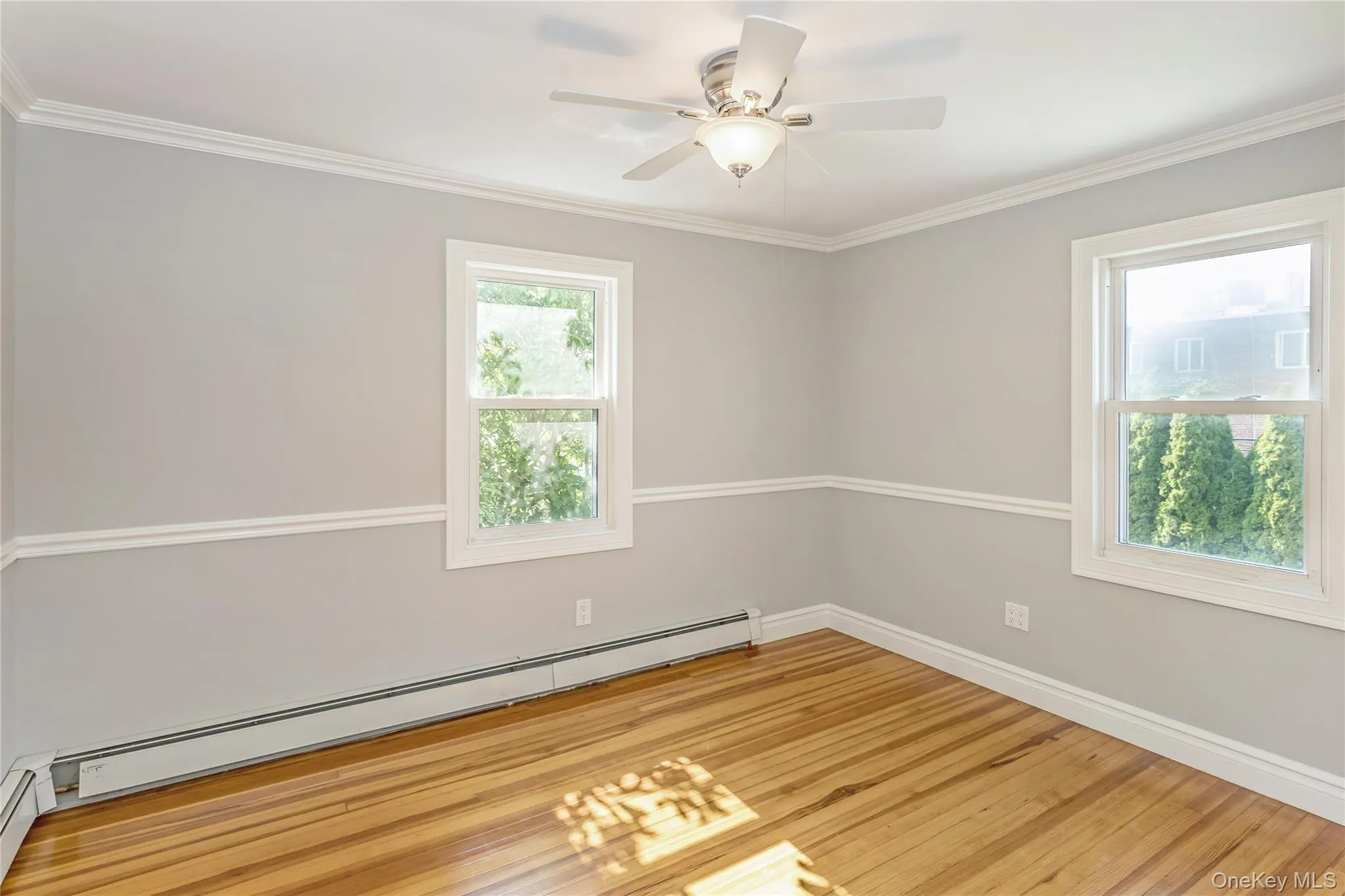 Unfurnished room with crown molding, light wood-type flooring, baseboard heating, and ceiling fan Unfurnished room with crown molding, light wood-type flooring, baseboard heating, and ceiling fan
