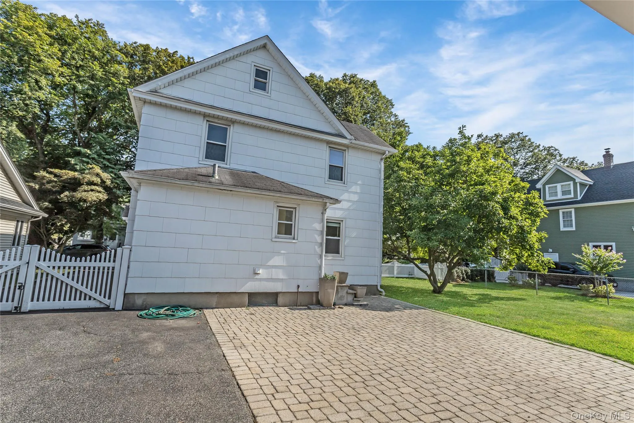 View of side of home with a gate, a patio area, and a shingled roof View of side of home with a gate, a patio area, and a shingled roof