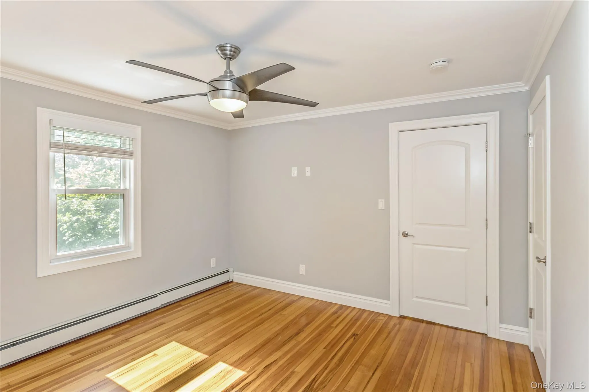 Unfurnished room with crown molding, a baseboard heating unit, light wood-style flooring, and ceiling fan Unfurnished room with crown molding, a baseboard heating unit, light wood-style flooring, and ceiling fan