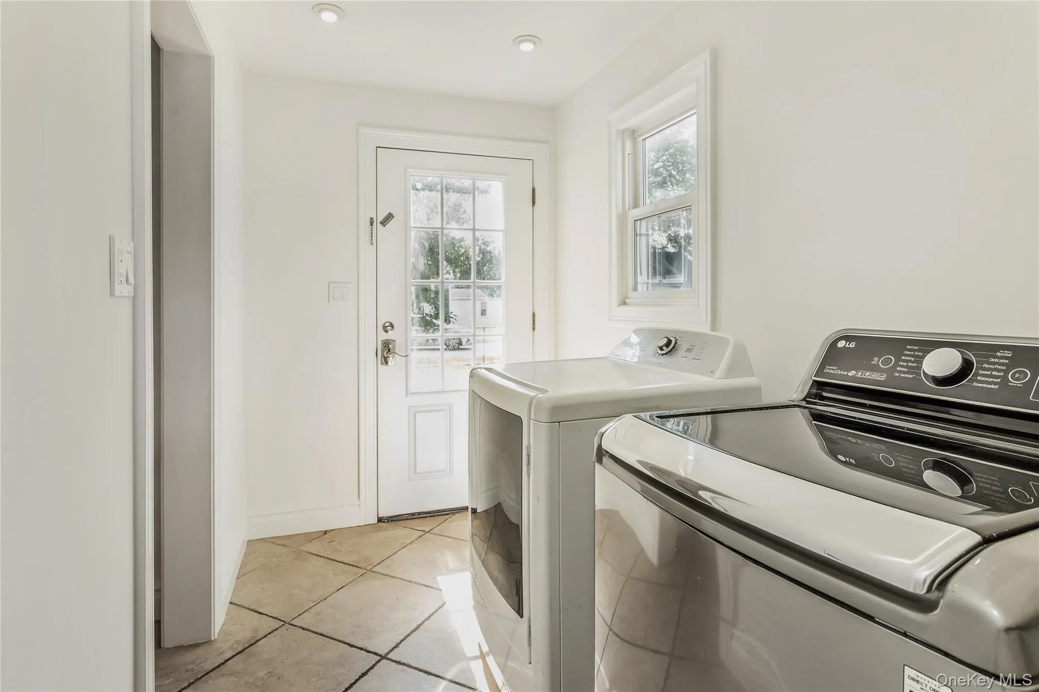 Laundry room with light tile patterned floors and separate washer and dryer Laundry room with light tile patterned floors and separate washer and dryer