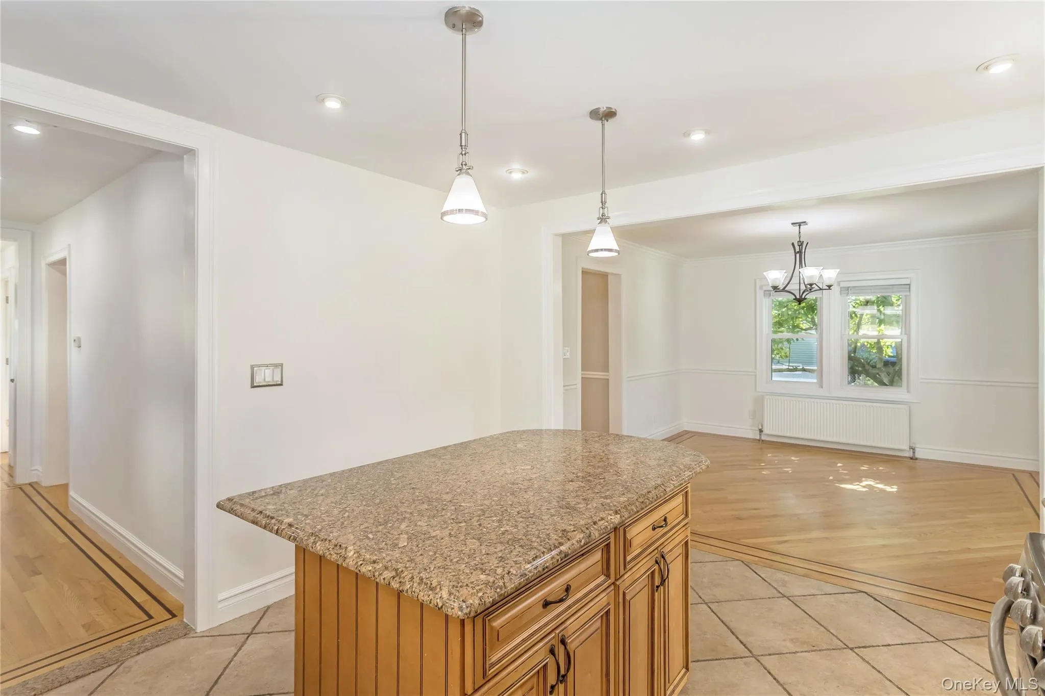 Kitchen featuring a center island, brown cabinets, pendant lighting, light stone counters, and radiator heating unit Kitchen featuring a center island, brown cabinets, pendant lighting, light stone counters, and radiator heating unit