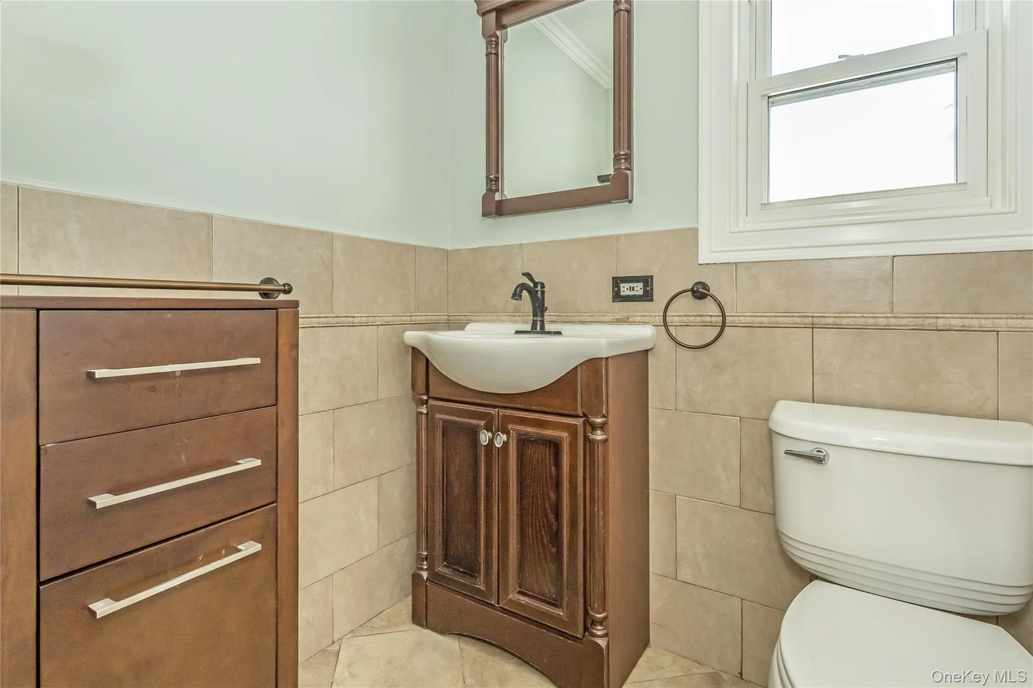 Half bathroom with vanity, light tile patterned flooring, wainscoting, and tile walls Half bathroom with vanity, light tile patterned flooring, wainscoting, and tile walls