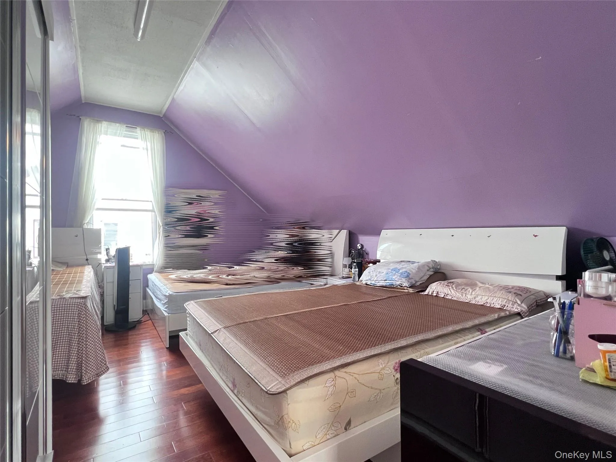 Room featuring sloped ceilings, purple wall finish, and wood-finish flooring Room featuring sloped ceilings, purple wall finish, and wood-finish flooring