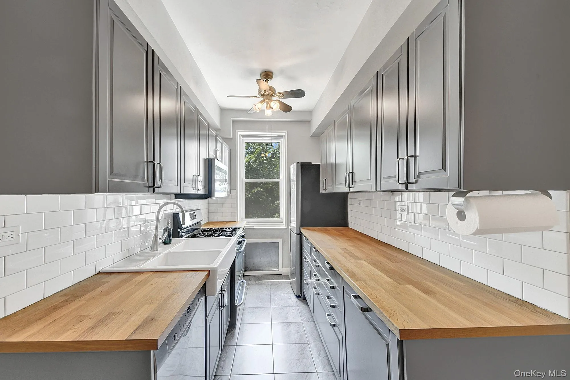Updated windowed galley kitchen with stainless steel appliances and gray shaker cabinets Updated windowed galley kitchen with stainless steel appliances and gray shaker cabinets