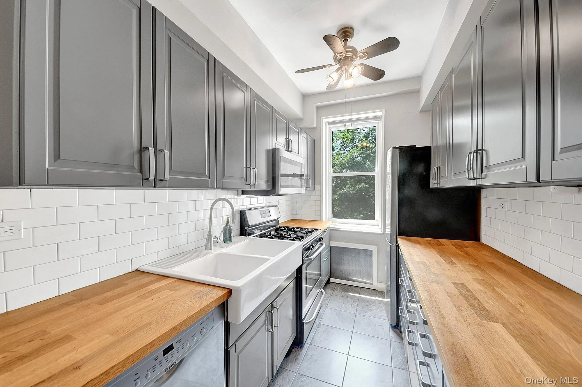 Updated windowed galley kitchen with stainless steel appliances and gray shaker cabinets Updated windowed galley kitchen with stainless steel appliances and gray shaker cabinets