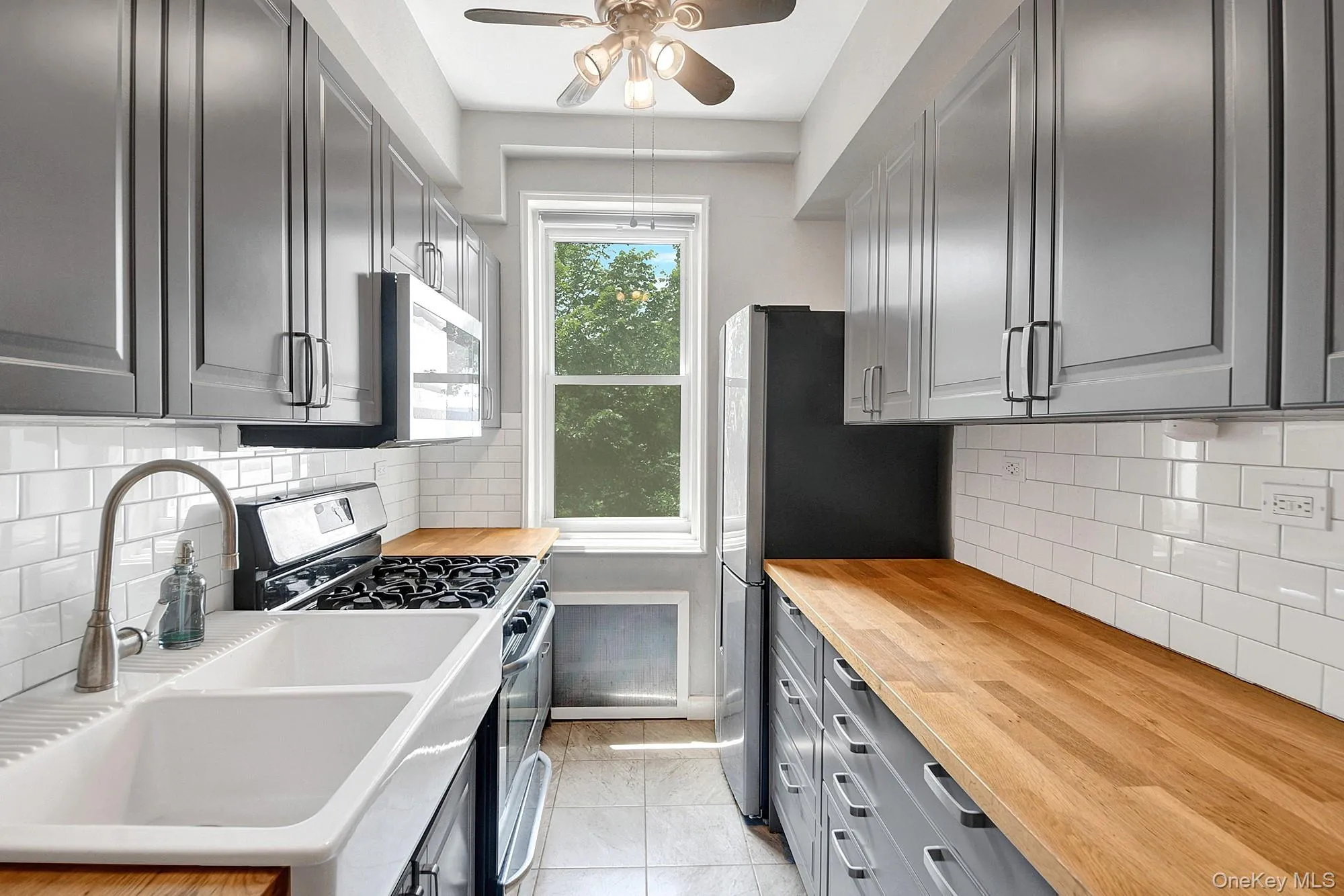 Updated windowed galley kitchen with stainless steel appliances and gray shaker cabinets Updated windowed galley kitchen with stainless steel appliances and gray shaker cabinets