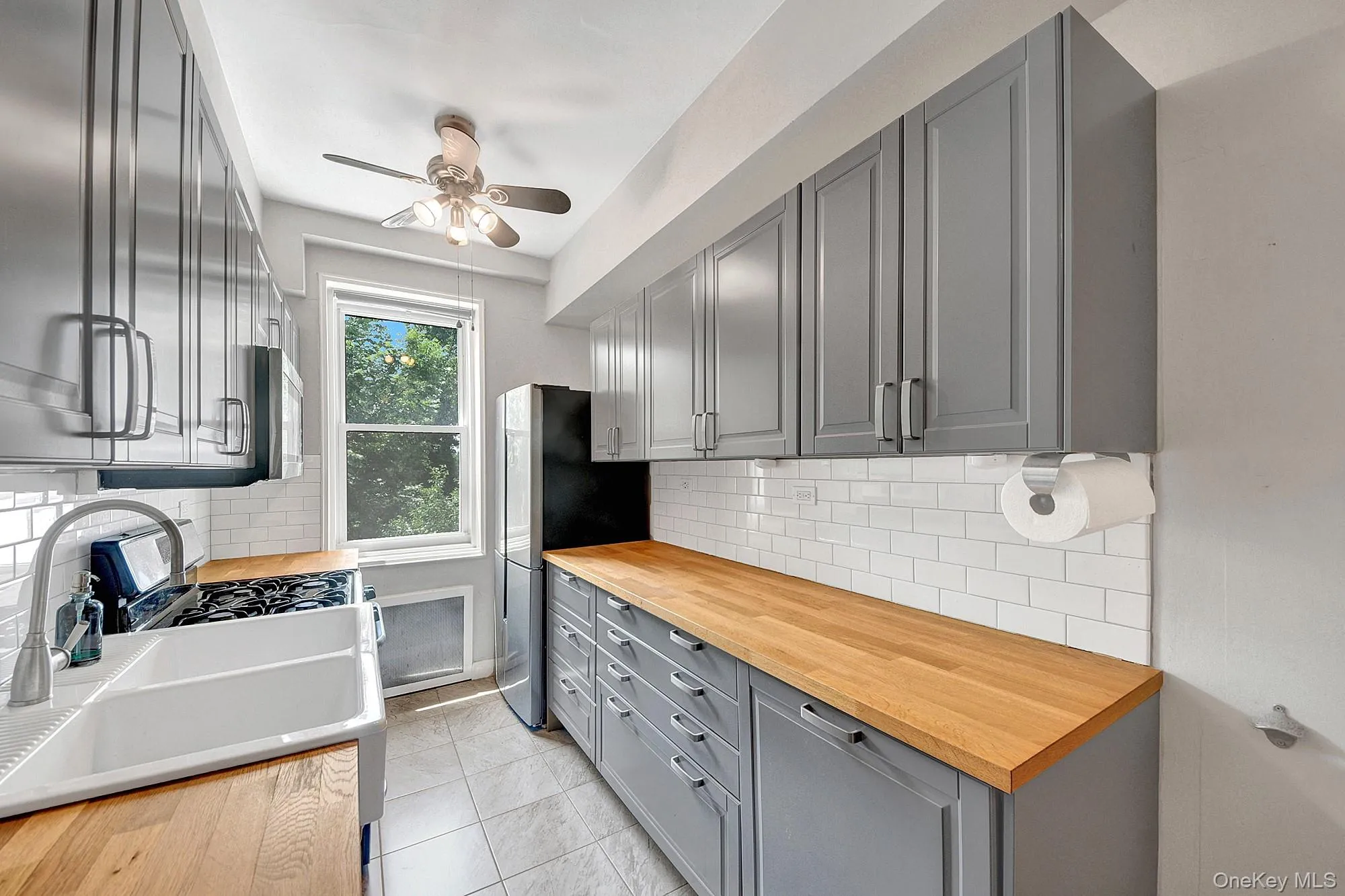 Updated windowed galley kitchen with stainless steel appliances and gray shaker cabinets Updated windowed galley kitchen with stainless steel appliances and gray shaker cabinets
