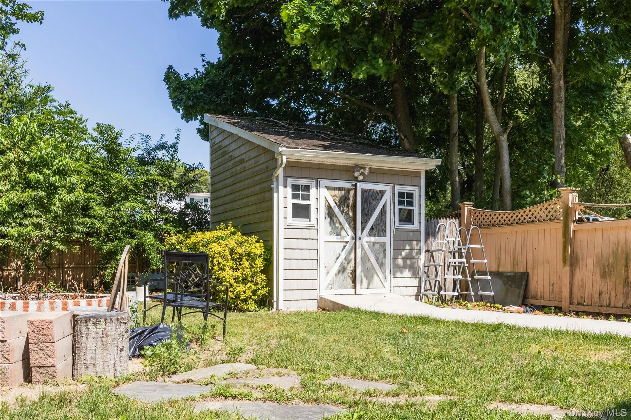 Storage shed with shingle siding, an asphalt shingle roof, and white-framed windows Storage shed with shingle siding, an asphalt shingle roof, and white-framed windows