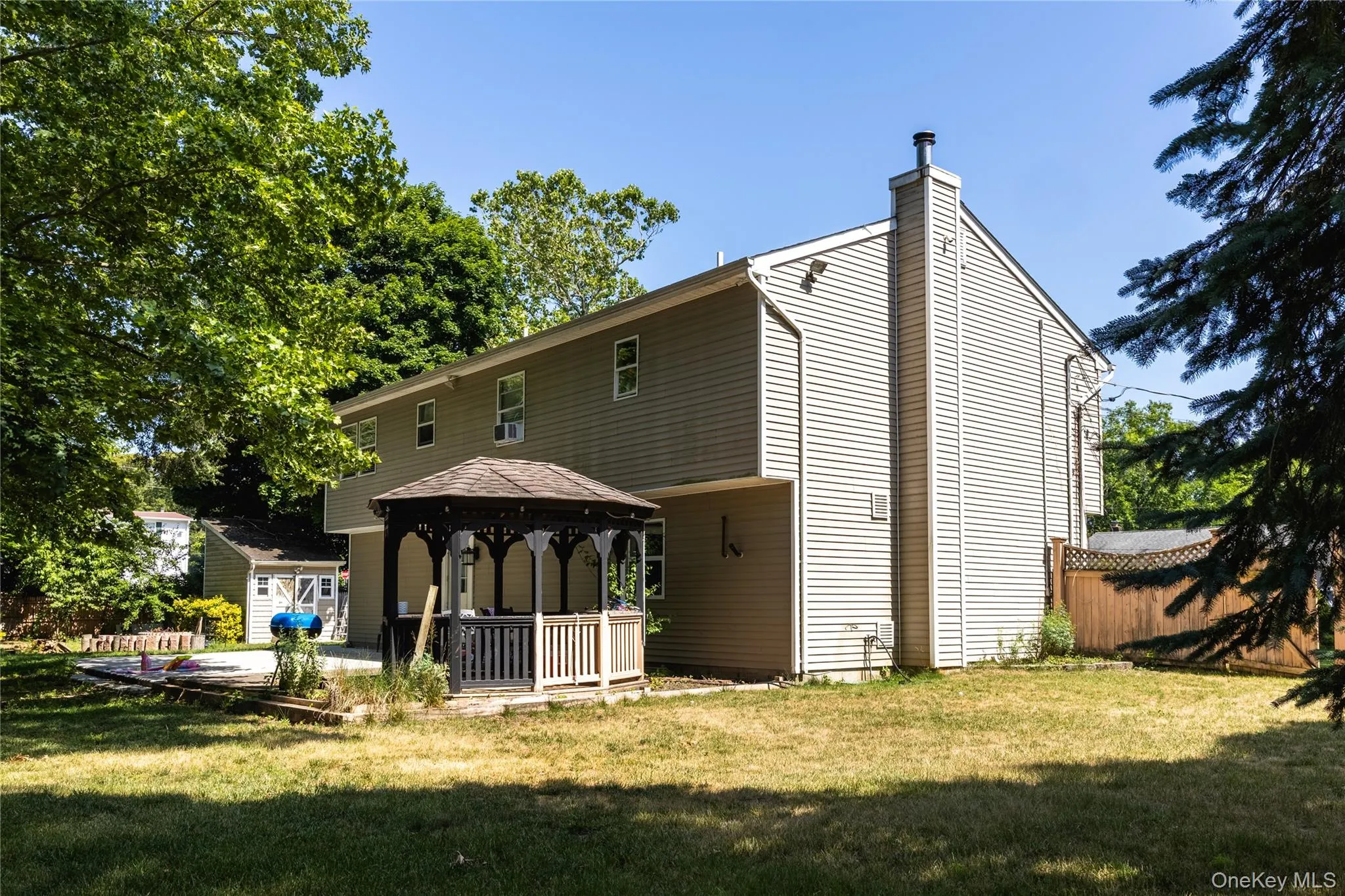 Exterior featuring light-colored siding, a prominent chimney, and a multi-level structure Exterior featuring light-colored siding, a prominent chimney, and a multi-level structure