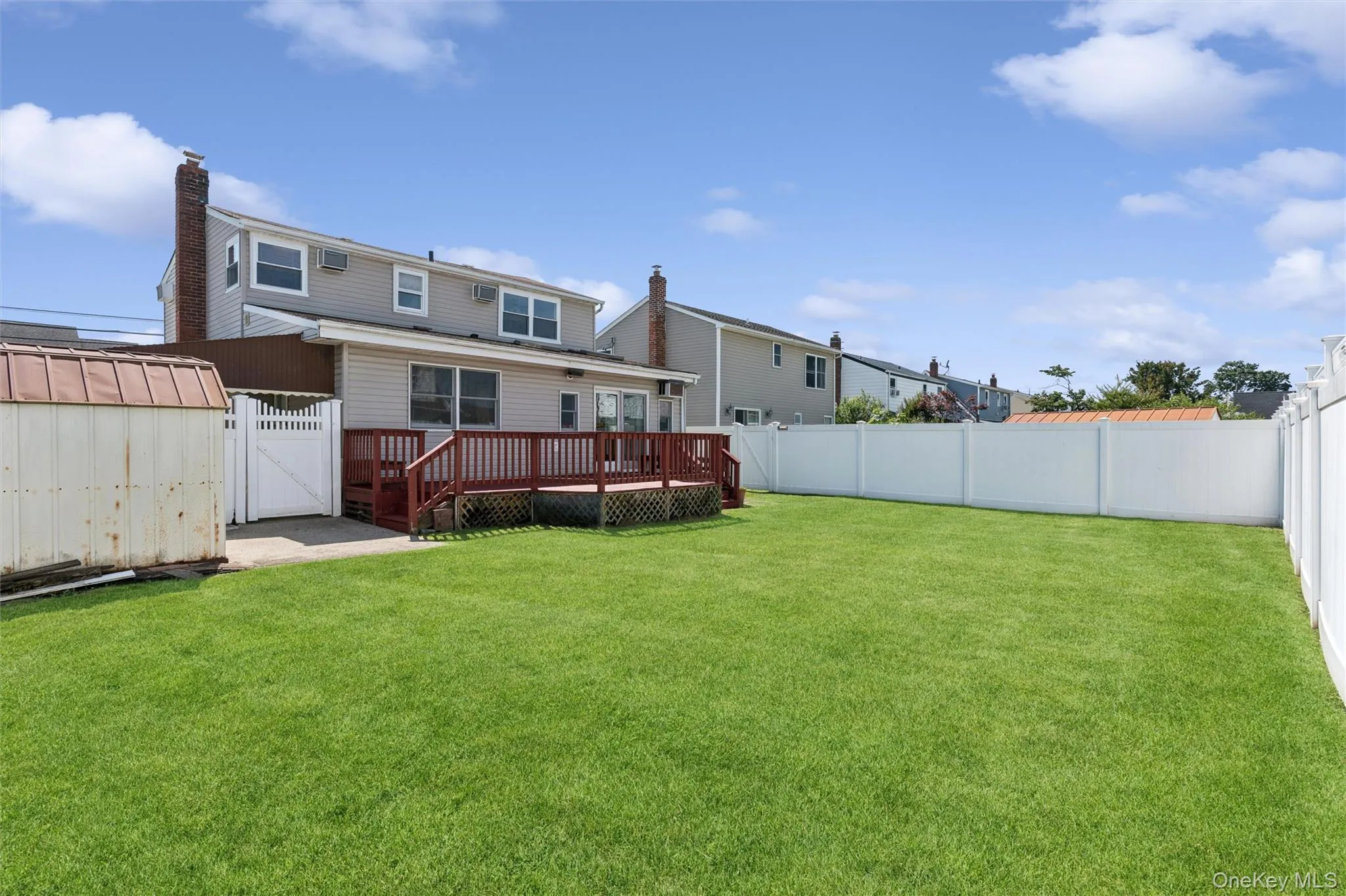 Expansive green lawn fully enclosed by a white privacy fence Expansive green lawn fully enclosed by a white privacy fence