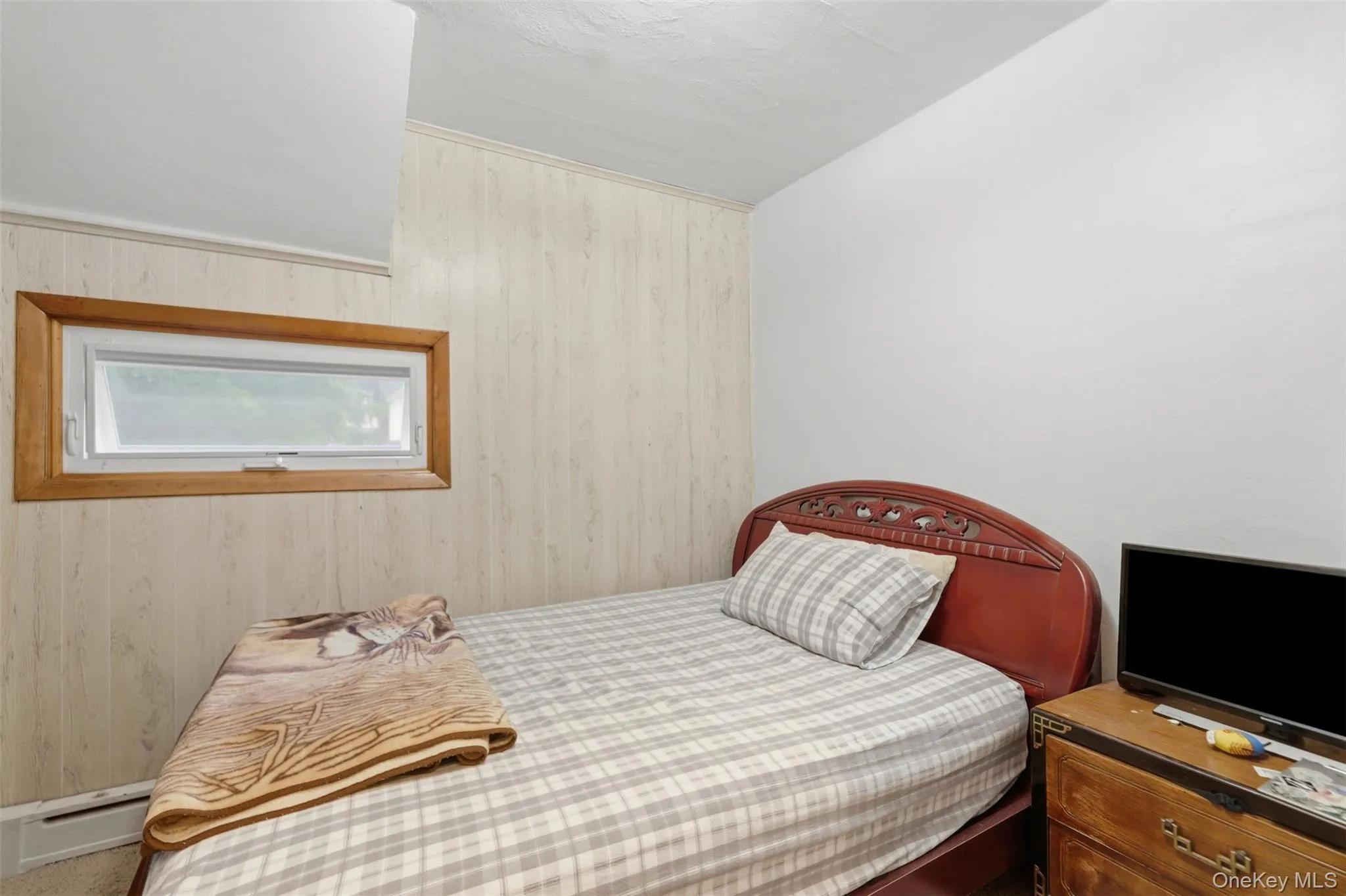 Room featuring wood-finish paneling, white painted walls, and a horizontal window with wood trim Room featuring wood-finish paneling, white painted walls, and a horizontal window with wood trim