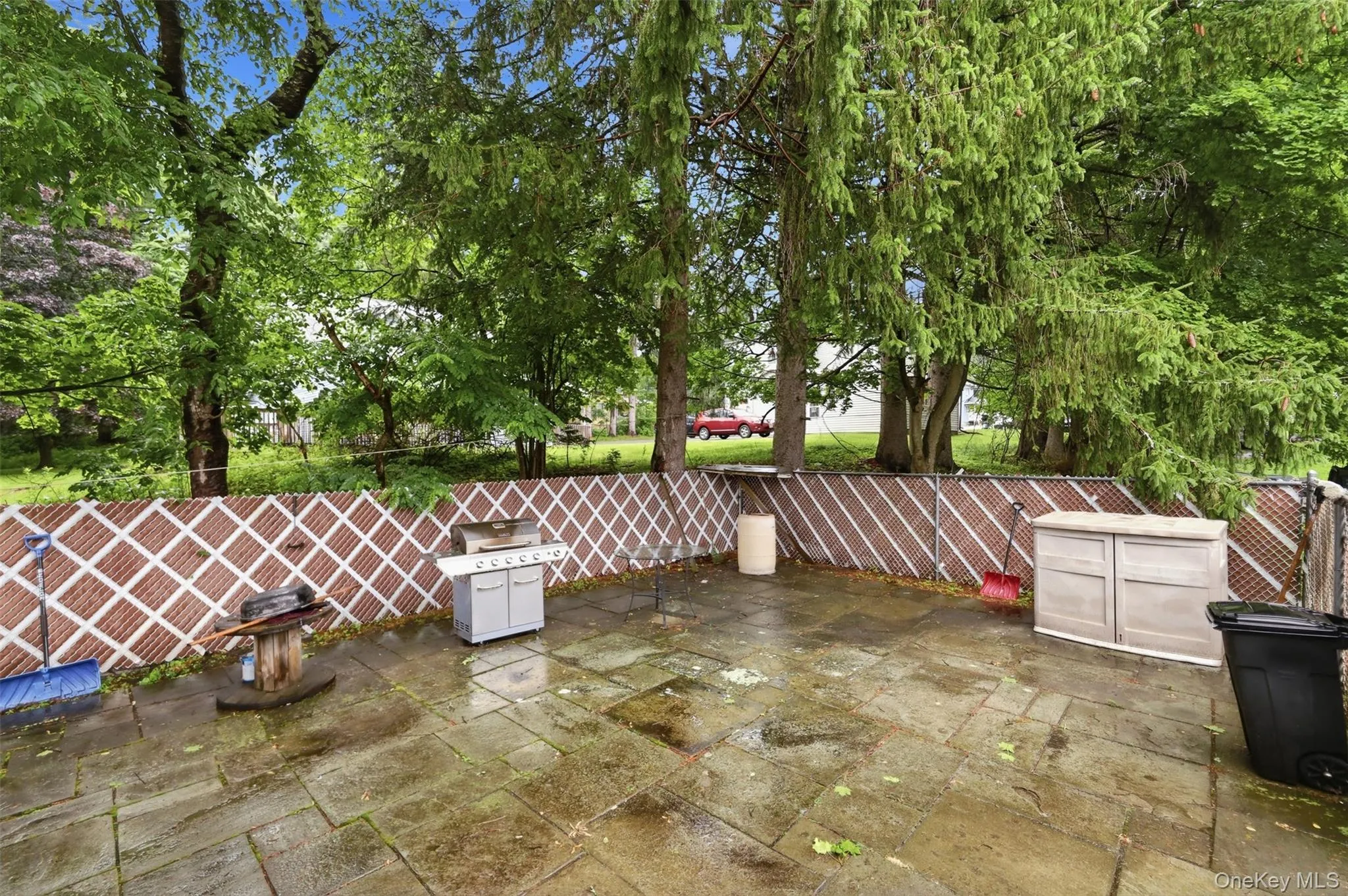 Expansive stone patio featuring a lattice-patterned privacy fence and mature trees Expansive stone patio featuring a lattice-patterned privacy fence and mature trees