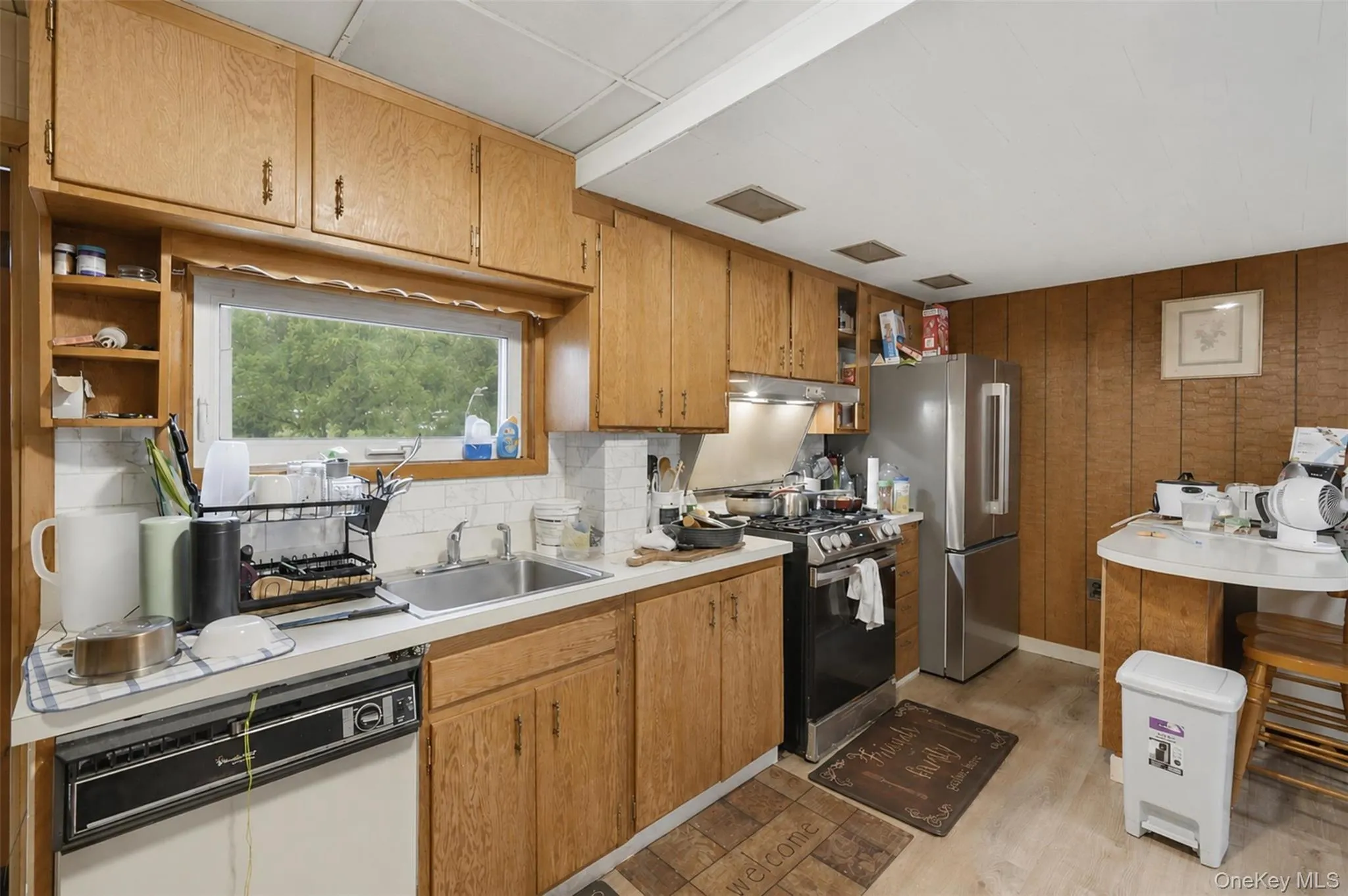 Kitchen featuring wood cabinetry, a stainless steel refrigerator, and a gas range Kitchen featuring wood cabinetry, a stainless steel refrigerator, and a gas range