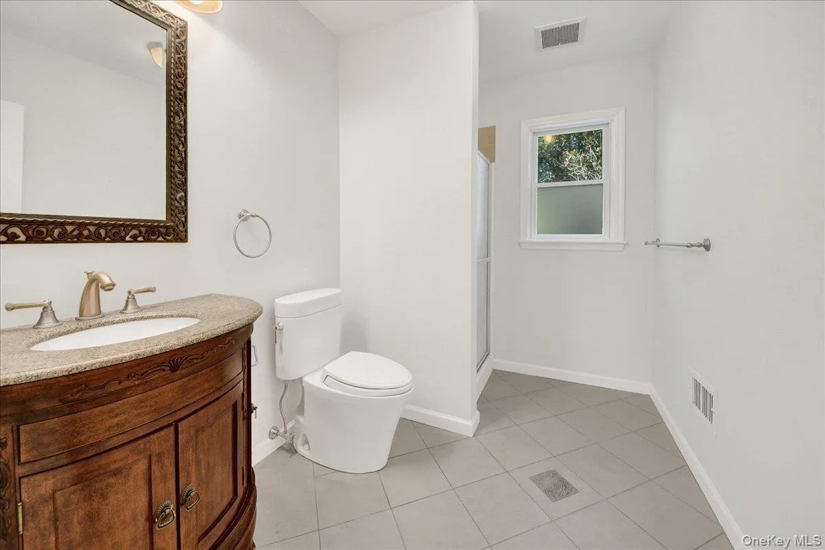 Bathroom featuring a wood-finish vanity with a stone countertop, an undermount sink, and a framed mirror Bathroom featuring a wood-finish vanity with a stone countertop, an undermount sink, and a framed mirror