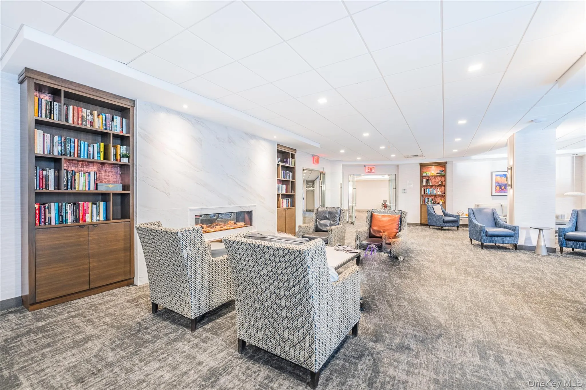 Carpeted living room featuring built in shelves, a high end fireplace, and recessed lighting Carpeted living room featuring built in shelves, a high end fireplace, and recessed lighting