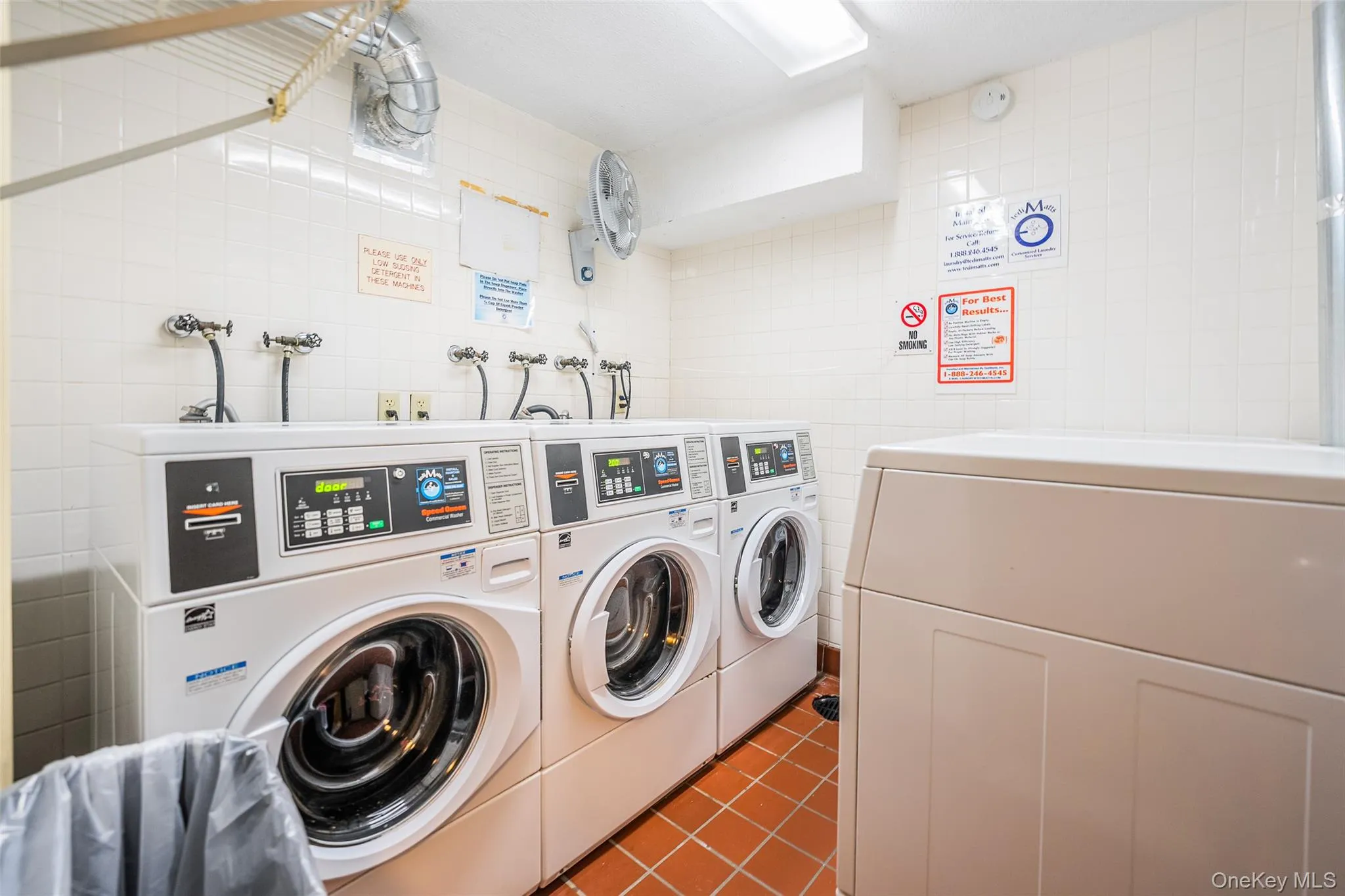 Shared laundry with tile walls and independent washer and dryer Shared laundry with tile walls and independent washer and dryer