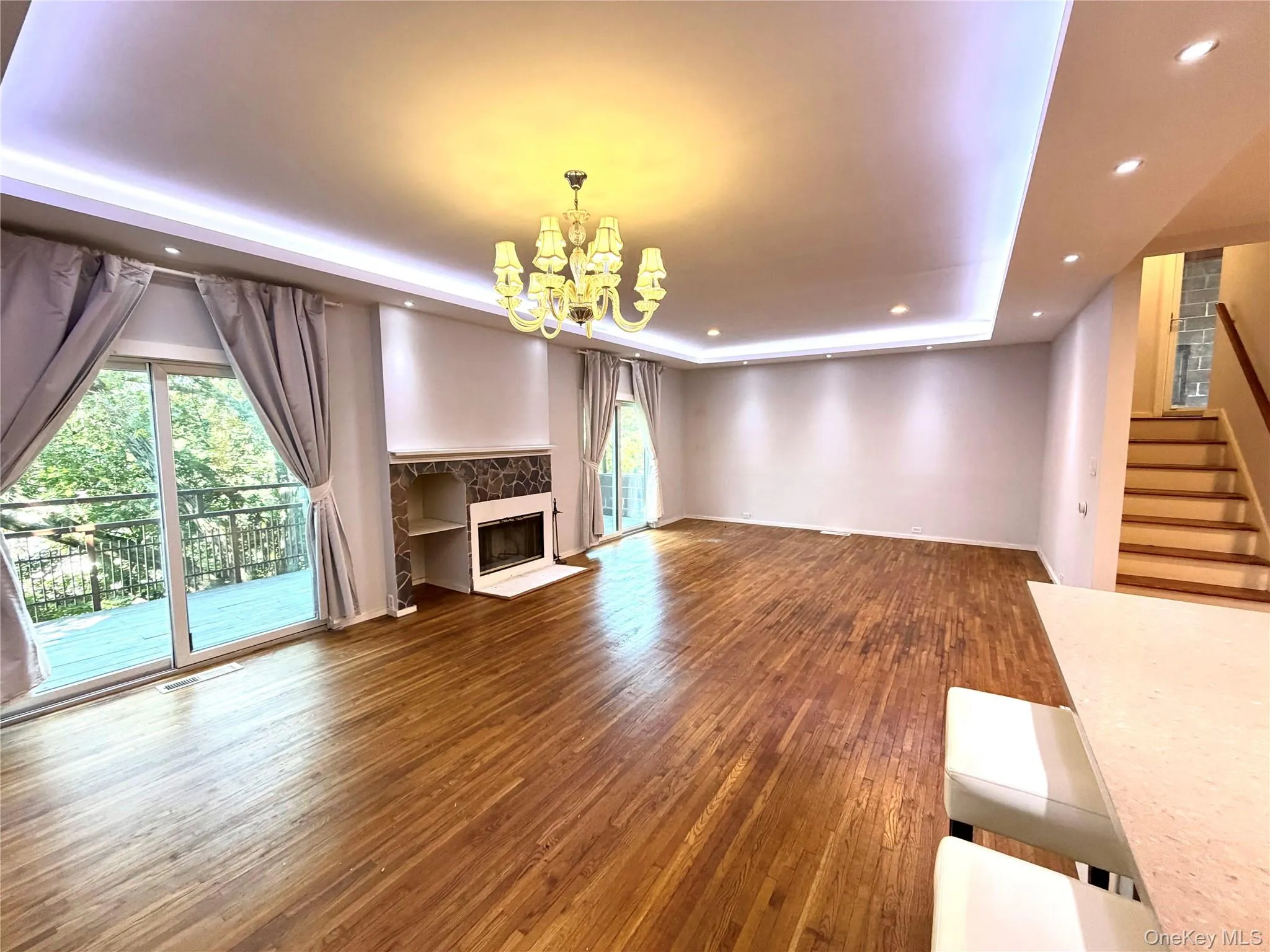 Spacious living area featuring wood-finish flooring, a fireplace with integrated shelving, and recessed lighting Spacious living area featuring wood-finish flooring, a fireplace with integrated shelving, and recessed lighting