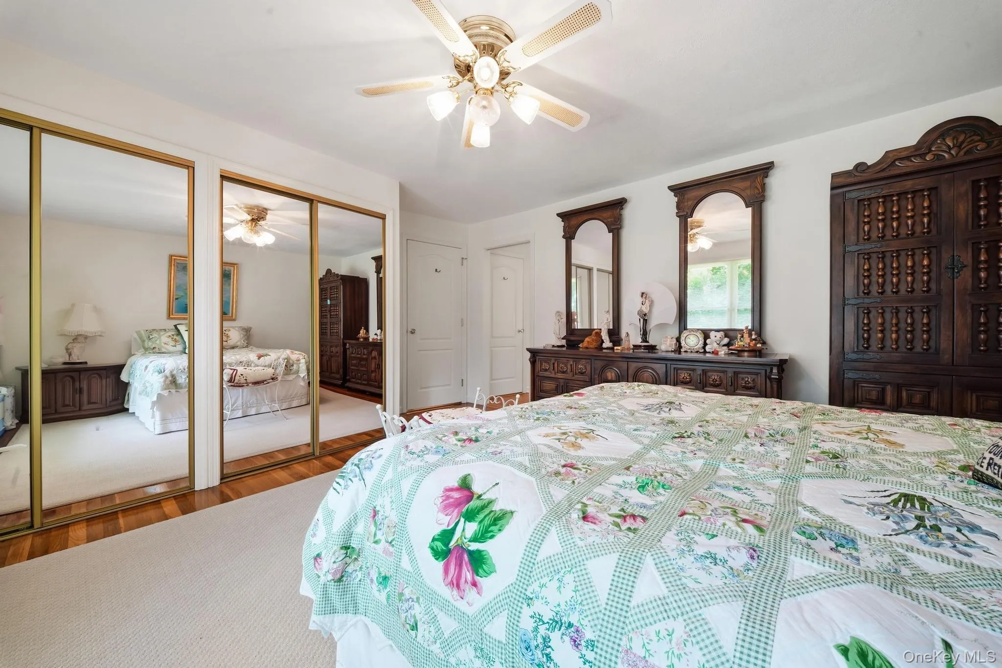 Bedroom featuring carpeted flooring, wood-finish flooring, and mirrored closet doors Bedroom featuring carpeted flooring, wood-finish flooring, and mirrored closet doors
