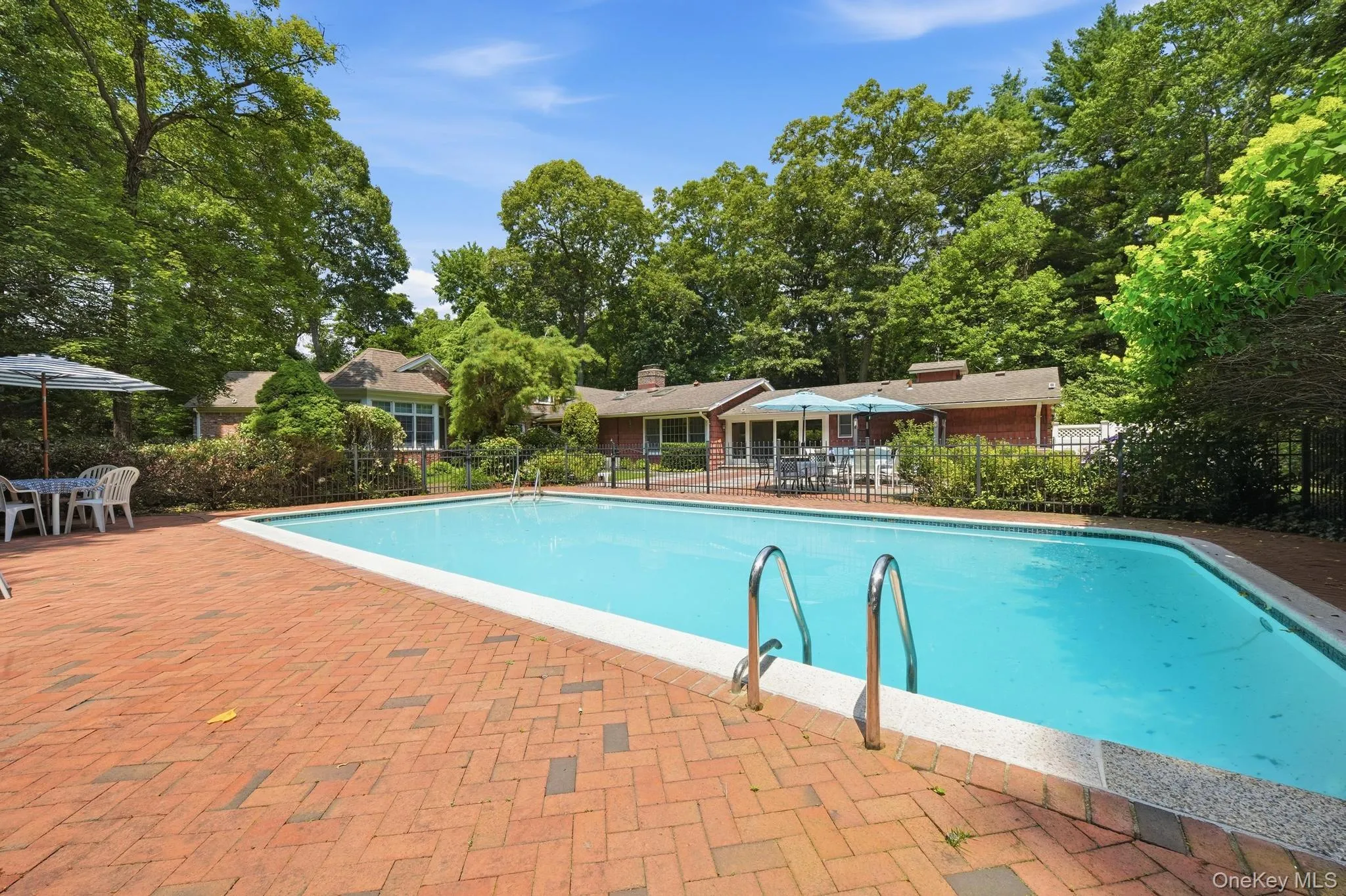 In-ground swimming pool featuring dual entry rails, surrounded by a herringbone brick patio In-ground swimming pool featuring dual entry rails, surrounded by a herringbone brick patio