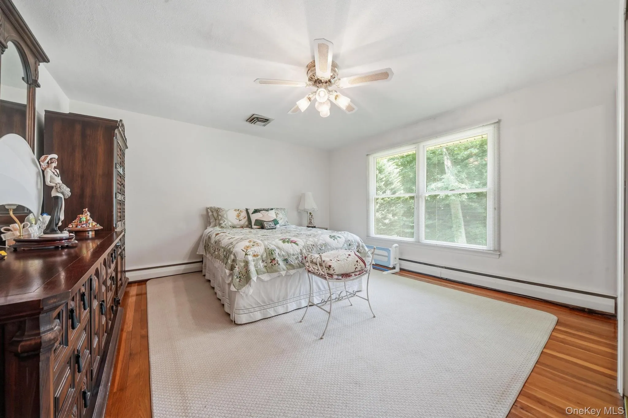 Interior room featuring a ceiling fan with integrated lighting, a large window, a partial wood-finish floor, and a light-colored area rug Interior room featuring a ceiling fan with integrated lighting, a large window, a partial wood-finish floor, and a light-colored area rug