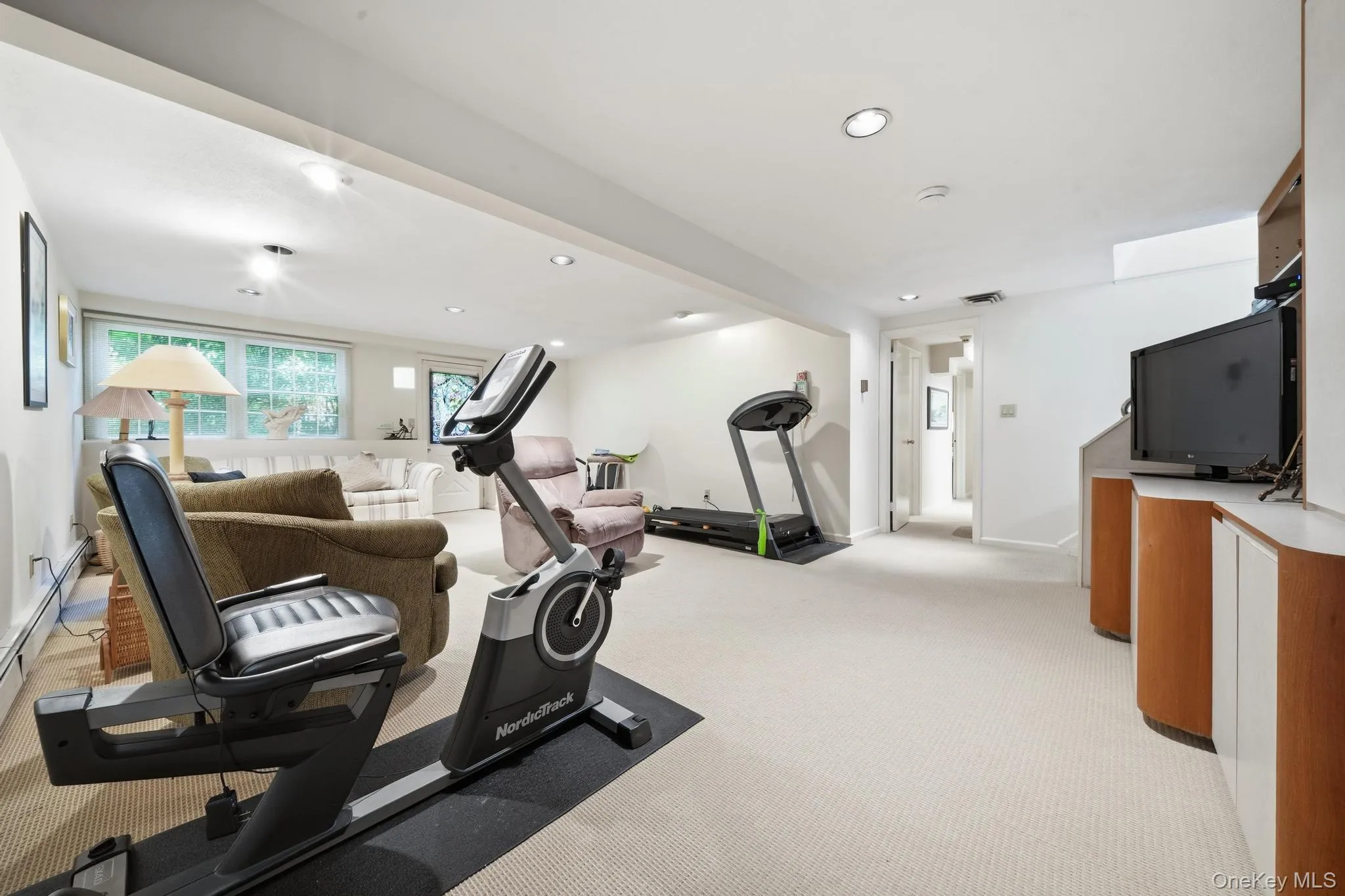Spacious lower-level area with recessed lighting, light-colored carpeting, a built-in entertainment console with wood-finish cabinetry, and a large window providing natural light Spacious lower-level area with recessed lighting, light-colored carpeting, a built-in entertainment console with wood-finish cabinetry, and a large window providing natural light