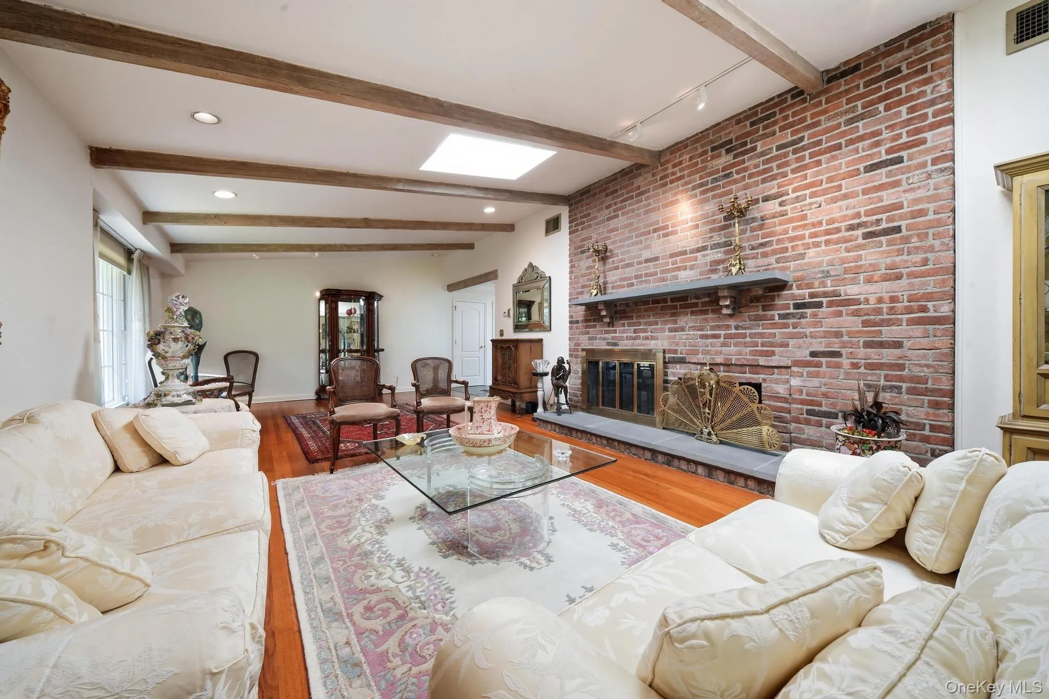 Spacious living area featuring a brick accent wall with a fireplace, a stone hearth, and a mantel shelf Spacious living area featuring a brick accent wall with a fireplace, a stone hearth, and a mantel shelf