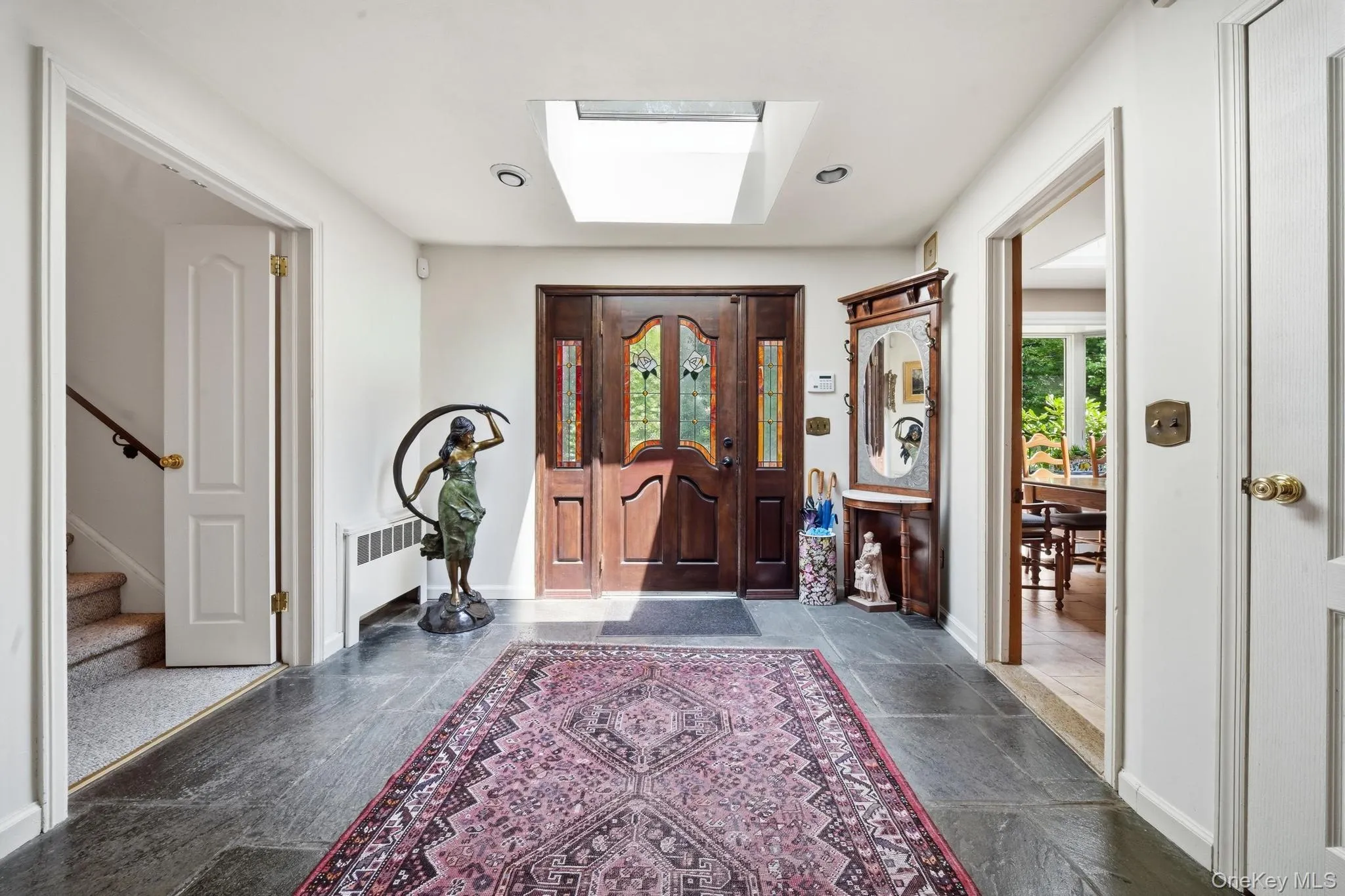 Entryway featuring a dark wood double door with decorative glass inserts, slate tile flooring, a skylight, and recessed lighting Entryway featuring a dark wood double door with decorative glass inserts, slate tile flooring, a skylight, and recessed lighting
