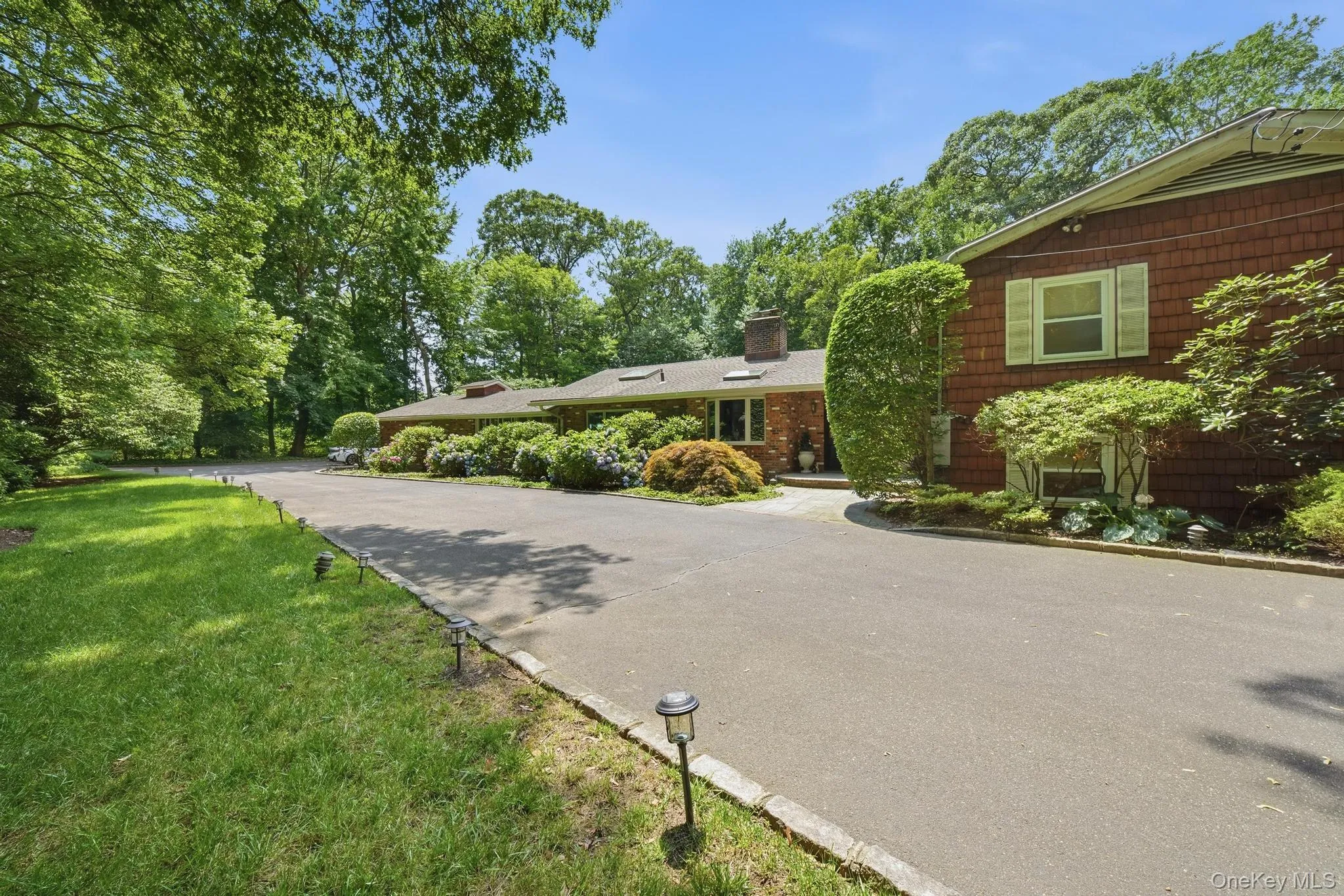 Curving asphalt driveway bordered by stone edging and landscape lighting Curving asphalt driveway bordered by stone edging and landscape lighting