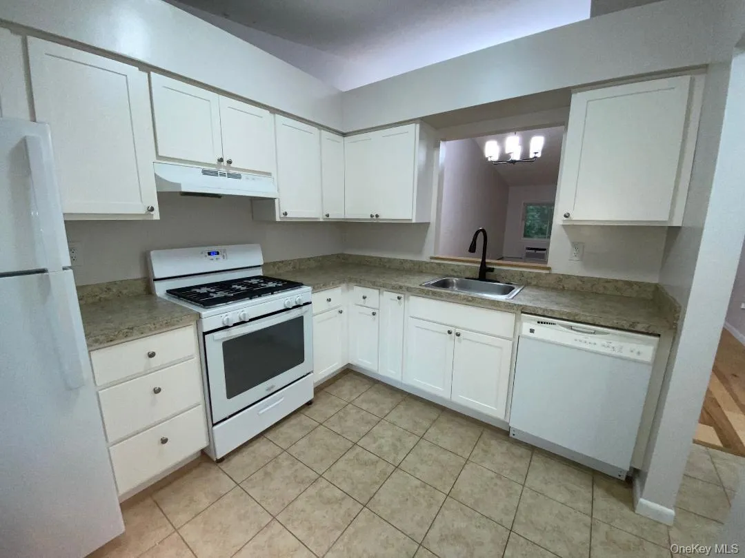 Updated eat kitchen featuring white cabinetry, a gas range, dishwasher and refrigerator, and ceramic tile flooring, and a stainless steel sink with a black gooseneck faucet Updated eat kitchen featuring white cabinetry, a gas range, dishwasher and refrigerator, and ceramic tile flooring, and a stainless steel sink with a black gooseneck faucet