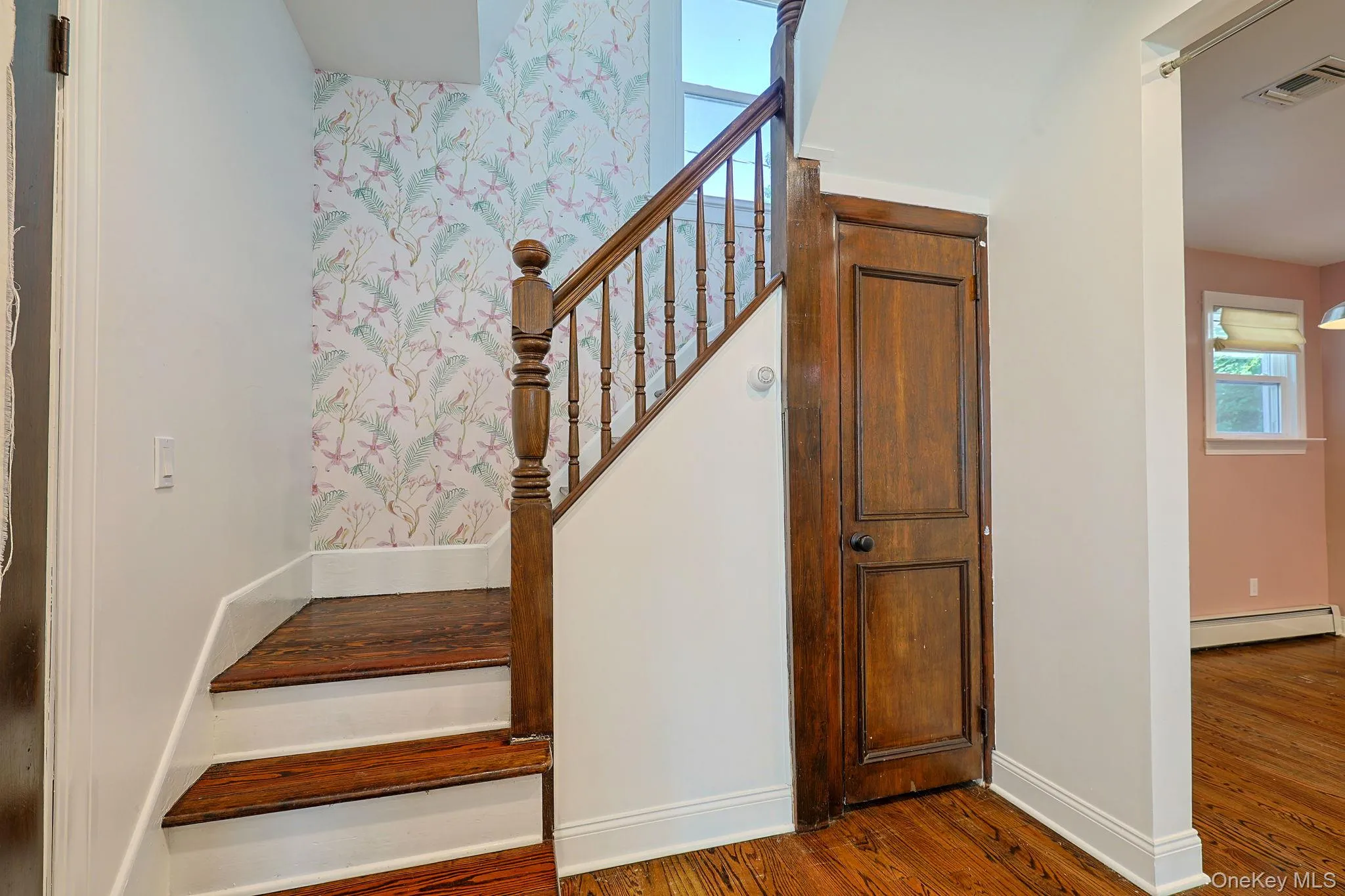 Staircase featuring wood-finish treads, white risers, and a wooden banister Staircase featuring wood-finish treads, white risers, and a wooden banister