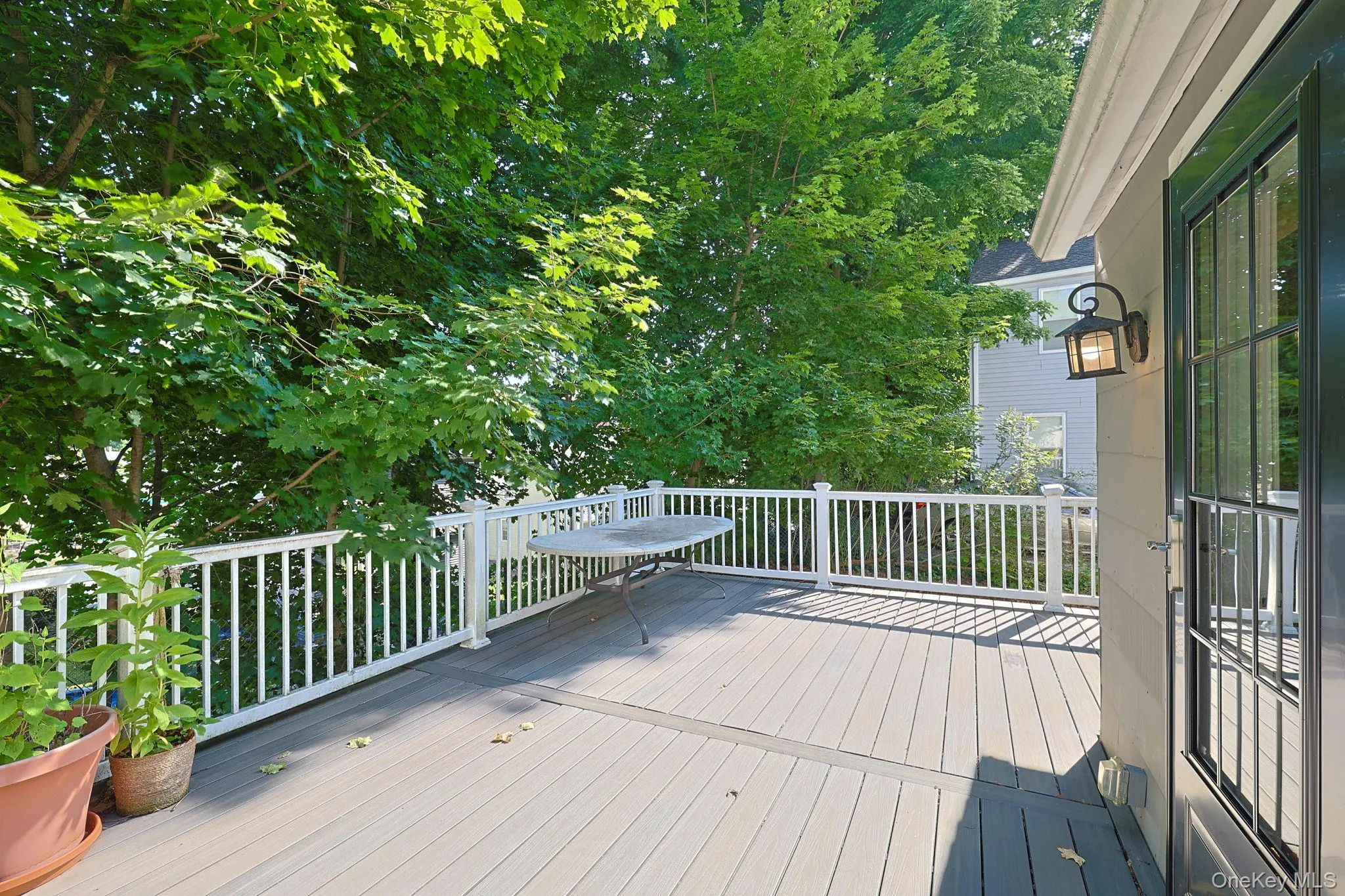 Spacious outdoor deck featuring composite decking, white railing, and mature tree canopy Spacious outdoor deck featuring composite decking, white railing, and mature tree canopy