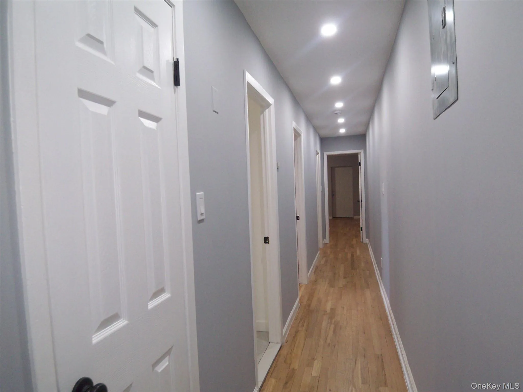 Hallway with wood-finish flooring, recessed lighting, and light gray painted walls Hallway with wood-finish flooring, recessed lighting, and light gray painted walls
