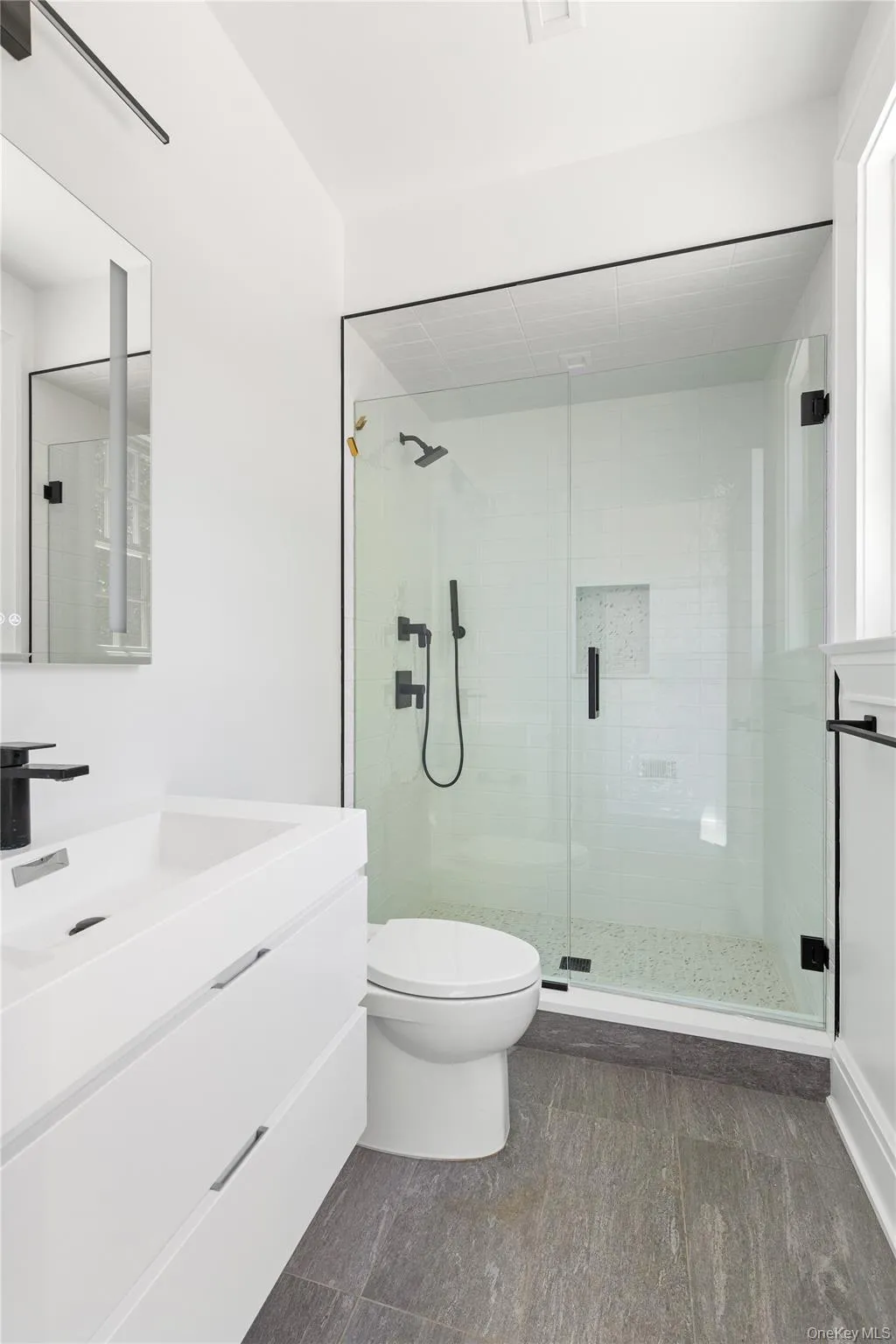 A stylish full bath serves the pool, mudroom, and main living areas with contemporary finishes and an oversized glass-enclosed shower. A stylish full bath serves the pool, mudroom, and main living areas with contemporary finishes and an oversized glass-enclosed shower.