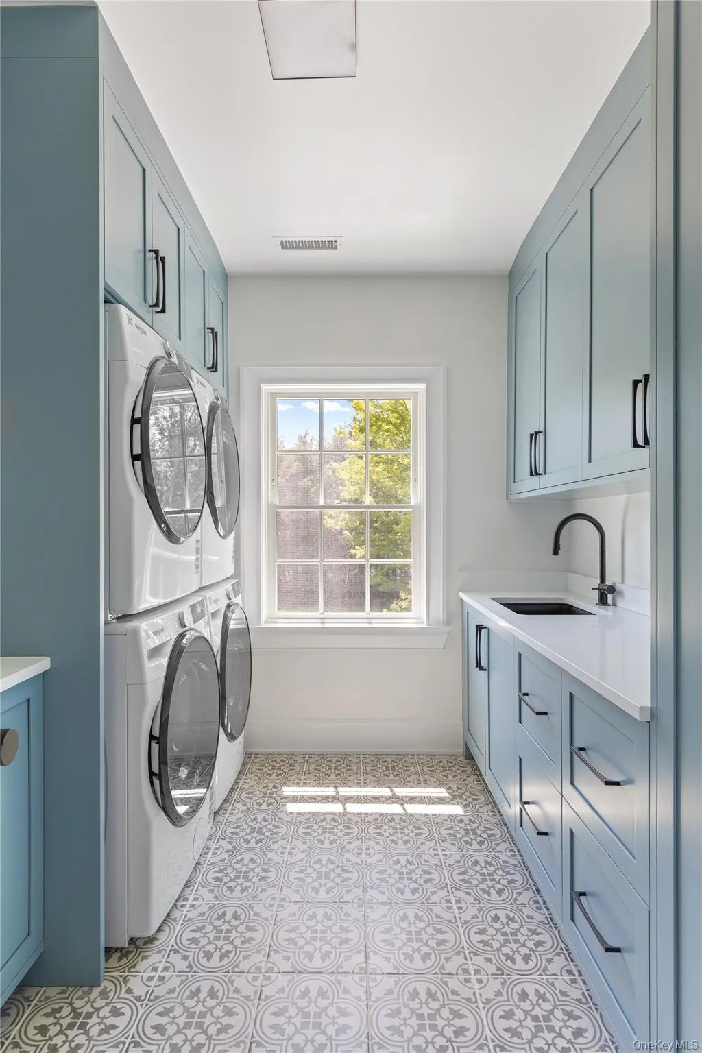 The beautifully designed second-floor laundry room features custom cabinetry, generous storage, dual washers and dryers, and a window that fills the space with natural light. The beautifully designed second-floor laundry room features custom cabinetry, generous storage, dual washers and dryers, and a window that fills the space with natural light.