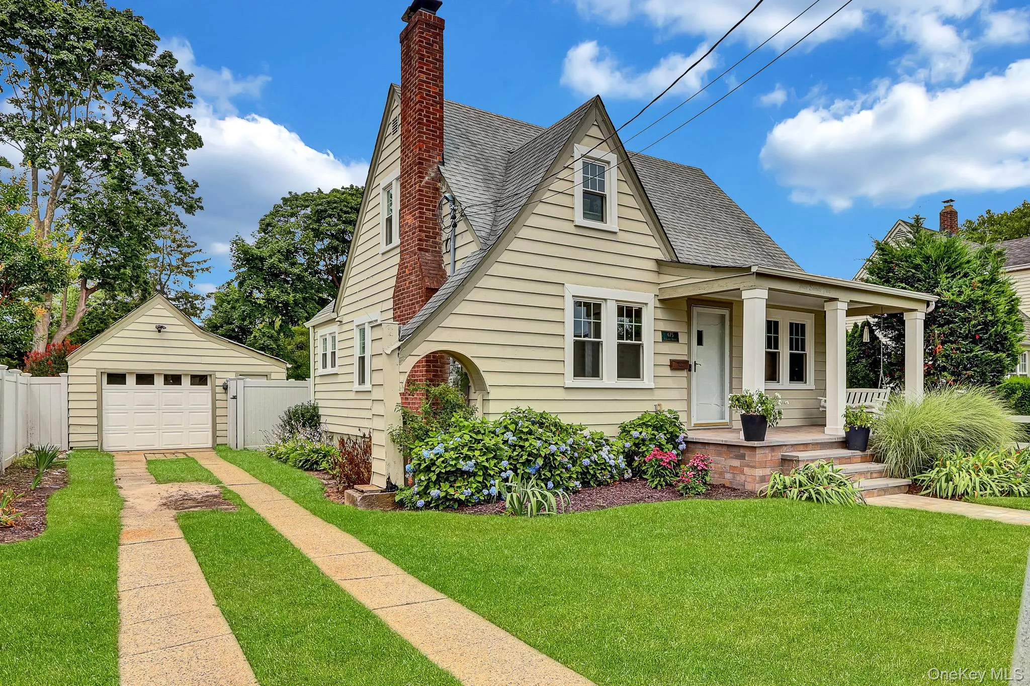 Charming residence featuring a covered front porch, brick chimney, and a detached single-car garage Charming residence featuring a covered front porch, brick chimney, and a detached single-car garage