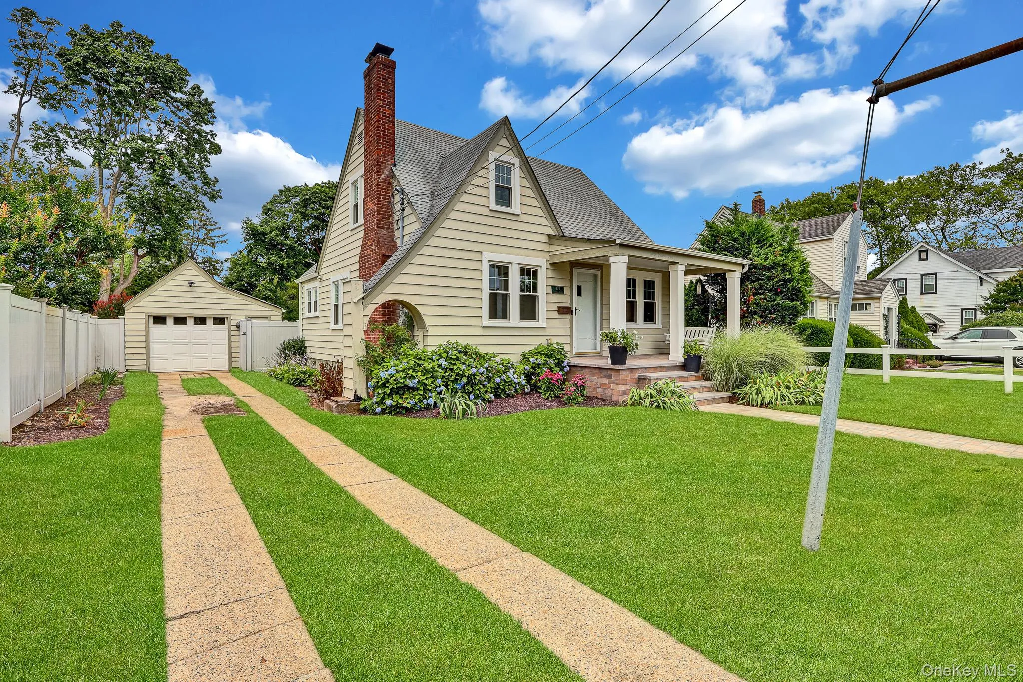 Gable-roof property featuring horizontal siding, a covered porch with white columns, and a brick chimney Gable-roof property featuring horizontal siding, a covered porch with white columns, and a brick chimney