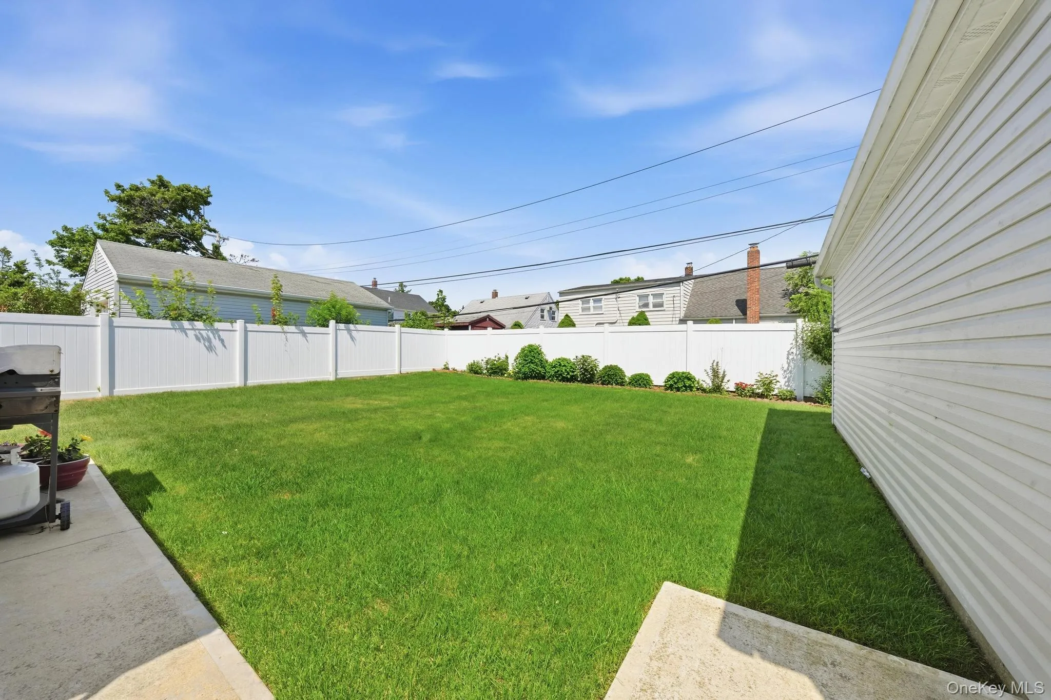 Expansive green lawn with a white privacy fence Expansive green lawn with a white privacy fence