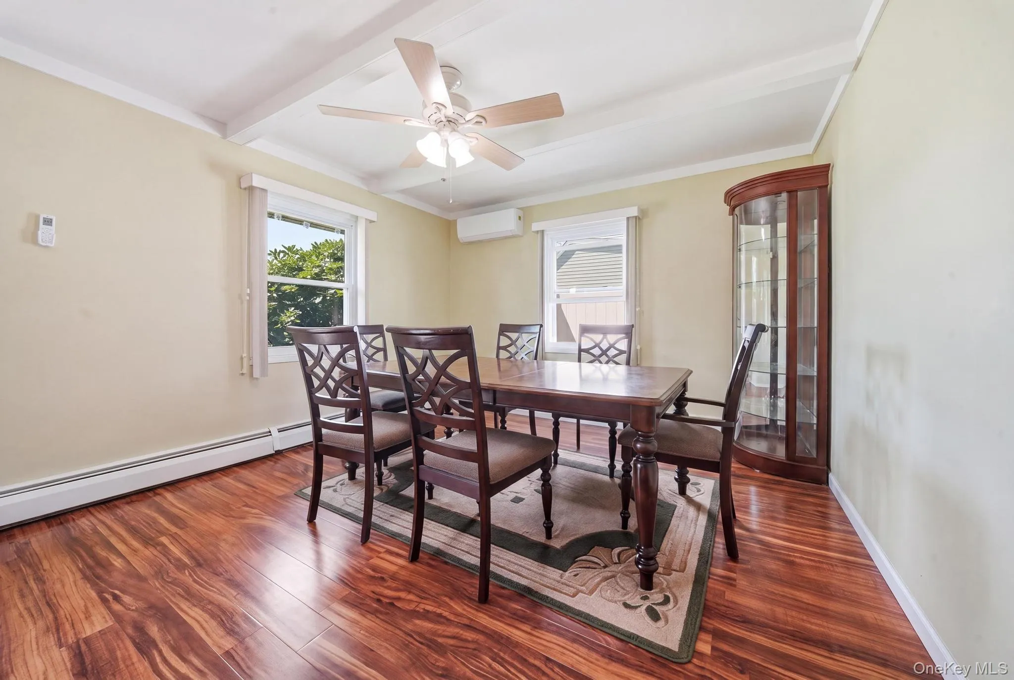 Spacious room featuring wood-finish flooring, two windows, and a ceiling fan with integrated lighting Spacious room featuring wood-finish flooring, two windows, and a ceiling fan with integrated lighting