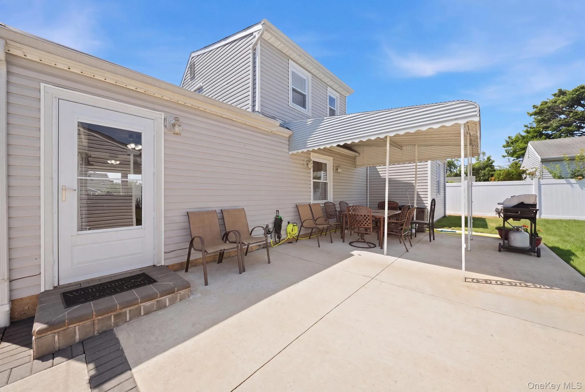 Expansive concrete patio area with an attached awning, providing shaded outdoor space Expansive concrete patio area with an attached awning, providing shaded outdoor space