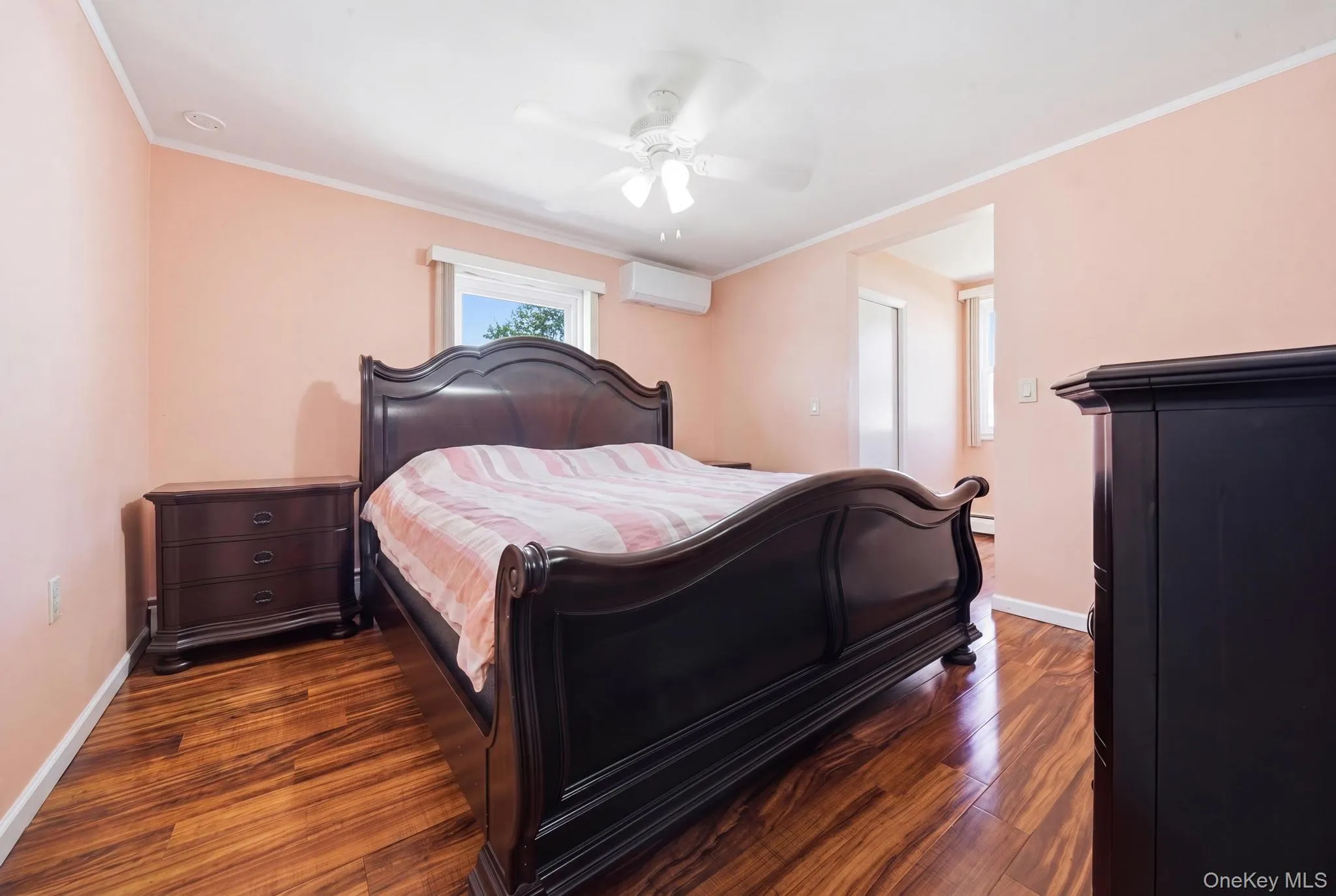Bedroom featuring wood-finish flooring, a ceiling fan, and a mini-split air conditioning unit Bedroom featuring wood-finish flooring, a ceiling fan, and a mini-split air conditioning unit