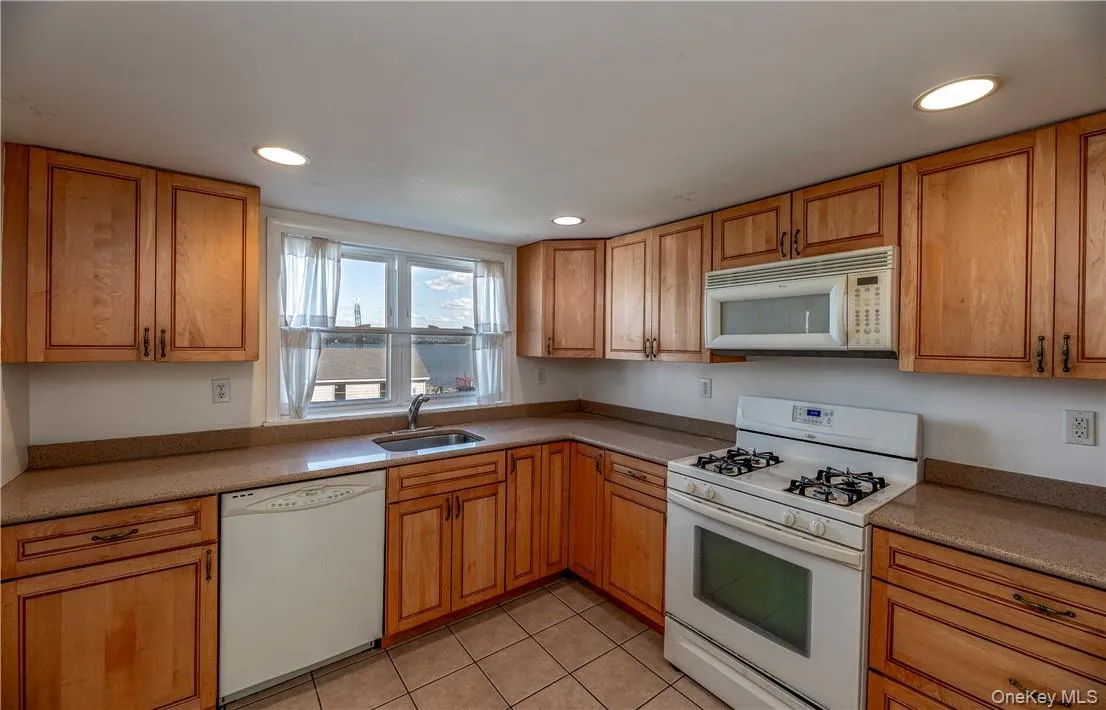Kitchen with white appliances, sink, and light tile patterned floors Kitchen with white appliances, sink, and light tile patterned floors