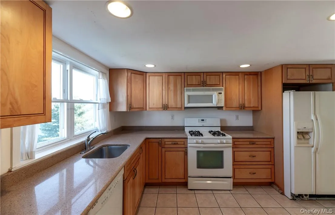 Kitchen featuring light tile patterned floors, sink, and white appliances Kitchen featuring light tile patterned floors, sink, and white appliances