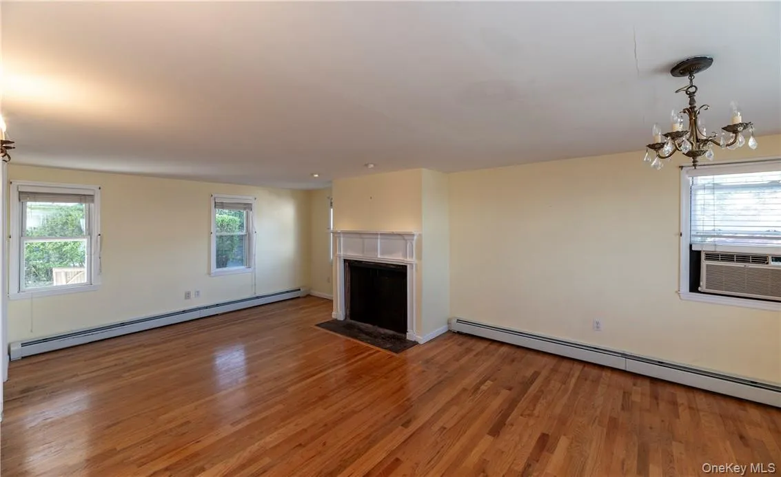 Unfurnished living room with hardwood / wood-style flooring, cooling unit, and a baseboard radiator Unfurnished living room with hardwood / wood-style flooring, cooling unit, and a baseboard radiator