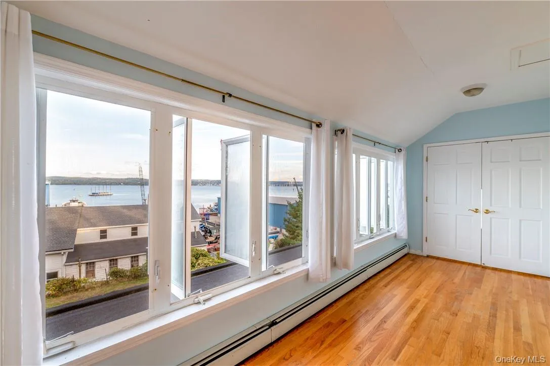 Unfurnished sunroom with a water view, vaulted ceiling, and a baseboard heating unit Unfurnished sunroom with a water view, vaulted ceiling, and a baseboard heating unit