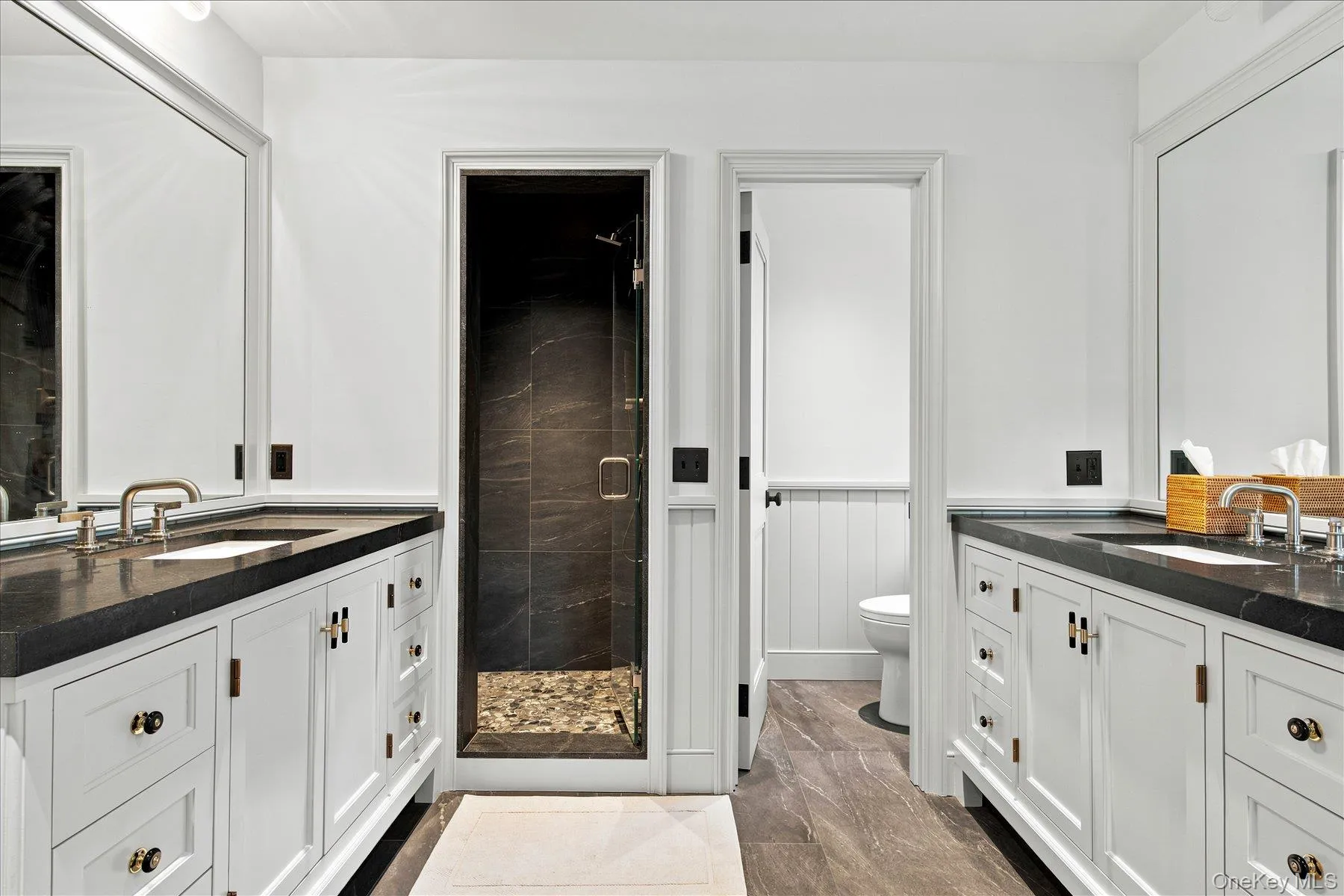 Dual vanity with stone countertops and undermount sinks, featuring white cabinetry and brushed nickel hardware Dual vanity with stone countertops and undermount sinks, featuring white cabinetry and brushed nickel hardware