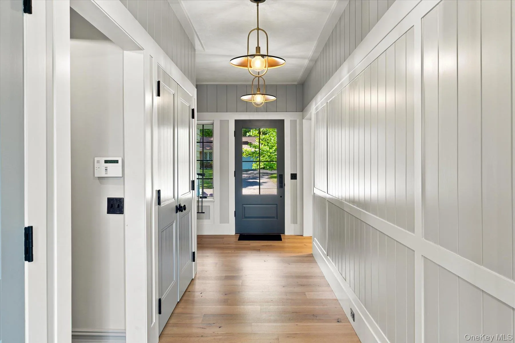 Entryway featuring wood-finish flooring, wainscoting, and shiplap paneling Entryway featuring wood-finish flooring, wainscoting, and shiplap paneling